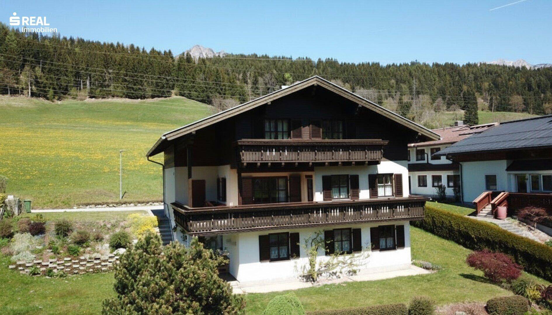 Traditionelles Haus mit Balkonen und weitem Blick auf die grüne Landschaft und Berge.