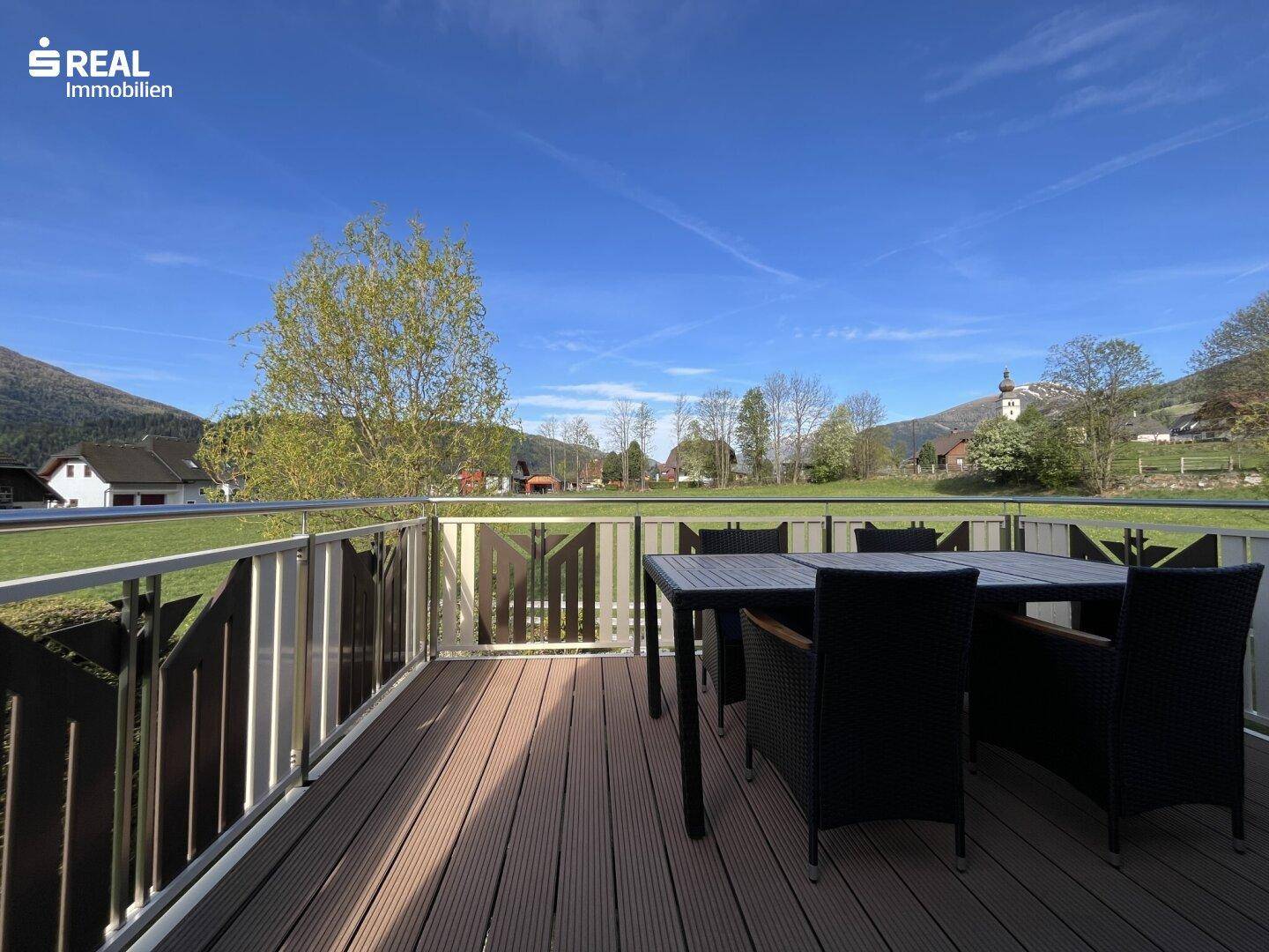 Geräumiger Balkon mit Holzboden und Sitzgelegenheiten, bietet weite Aussicht auf die Landschaft.