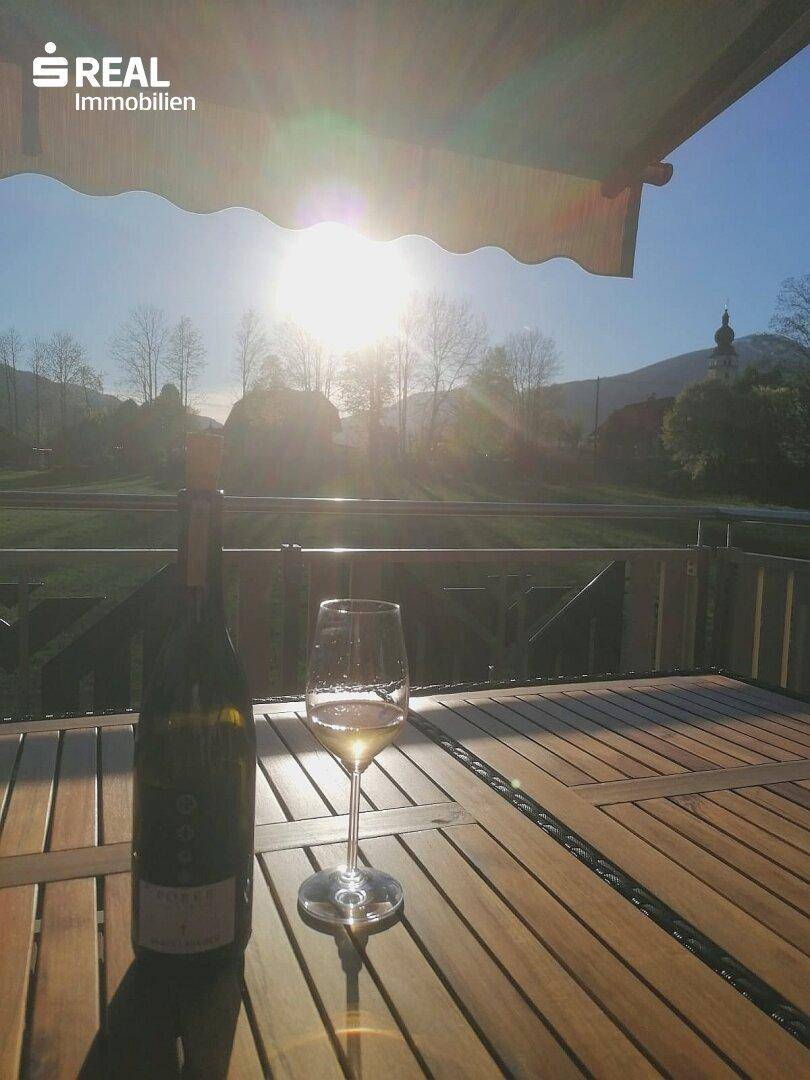 Sonniger Balkon mit Holztisch und Getränken, ideal für entspannte Stunden im Freien.