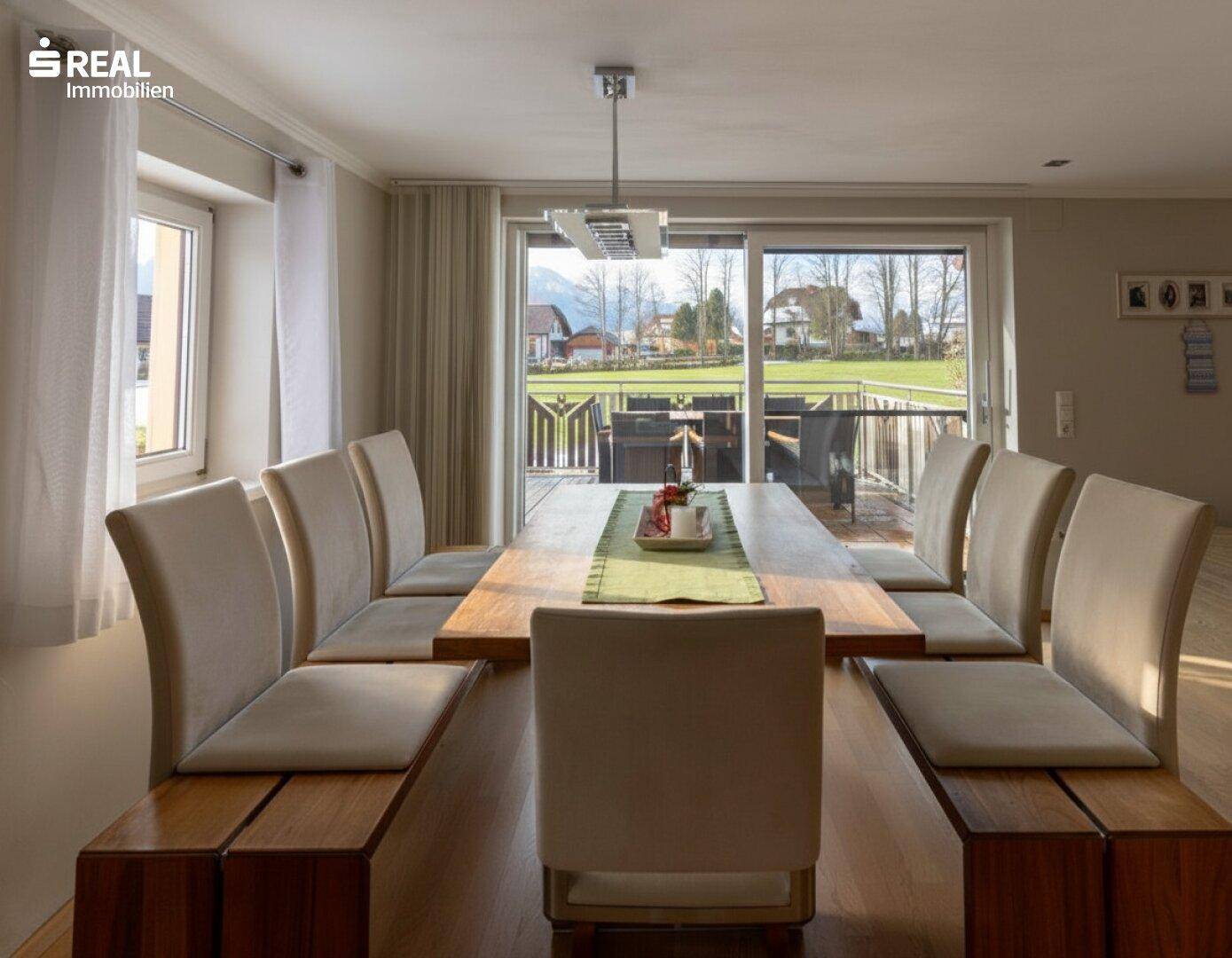 Geräumiger Essbereich mit Holztisch und bequemen Bänken, mit Zugang zum Balkon und Bergblick.