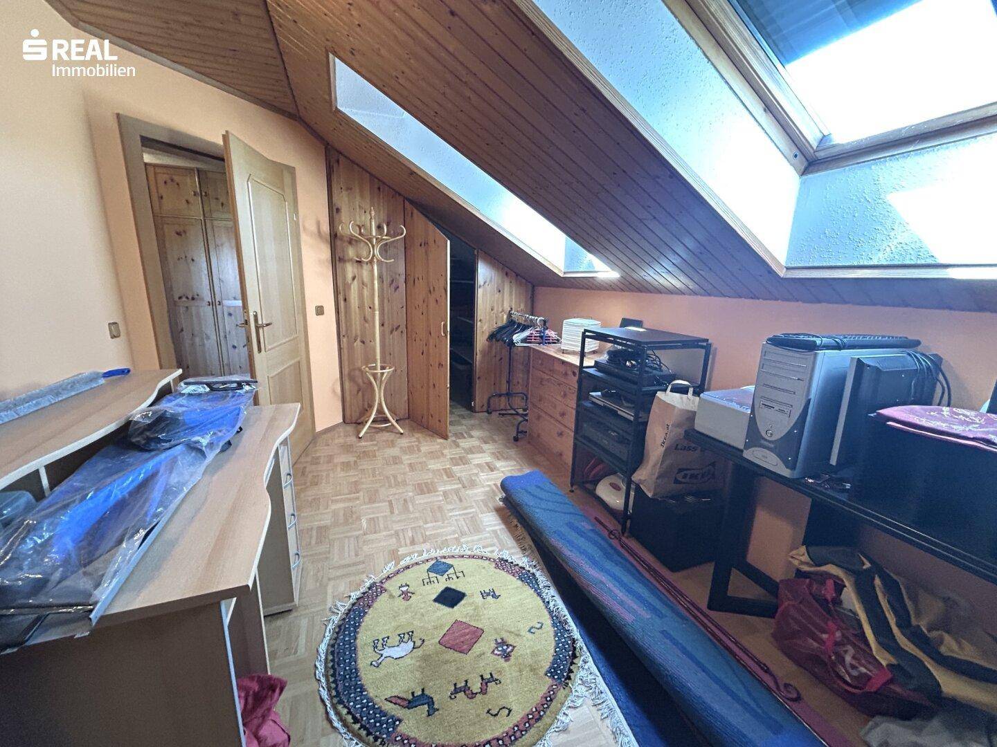 Dachgeschosszimmer mit Dachschrägen, Dachfenstern und Parkettboden, als Abstellraum genutzt.