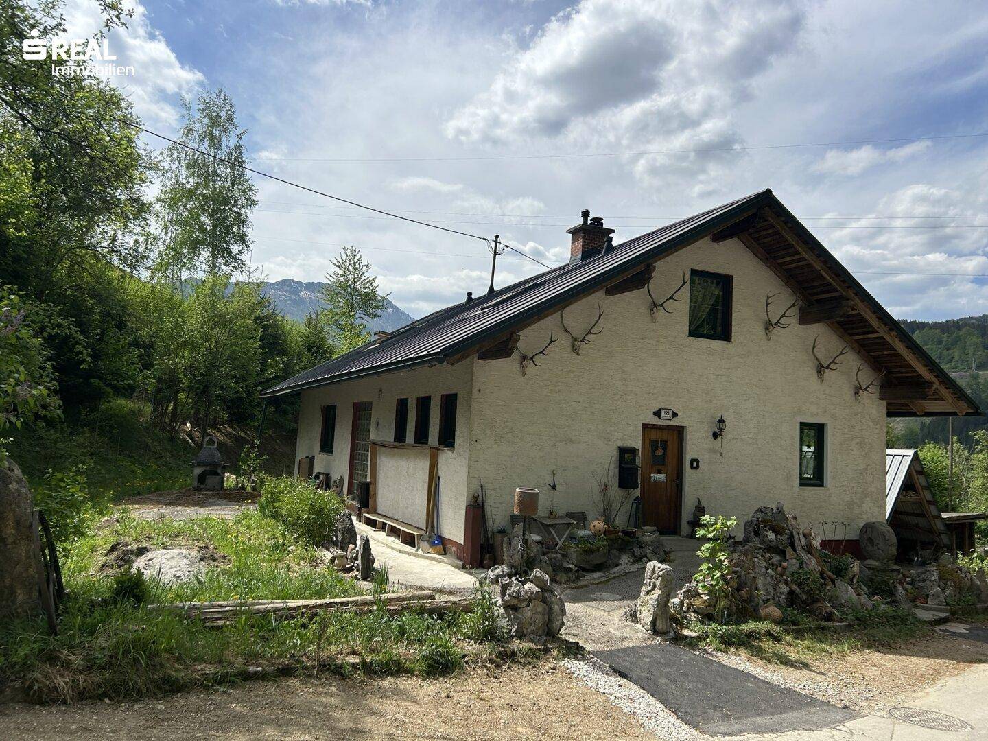Ländliches Haus mit traditionellen Geweihen an der Fassade und Bergblick.