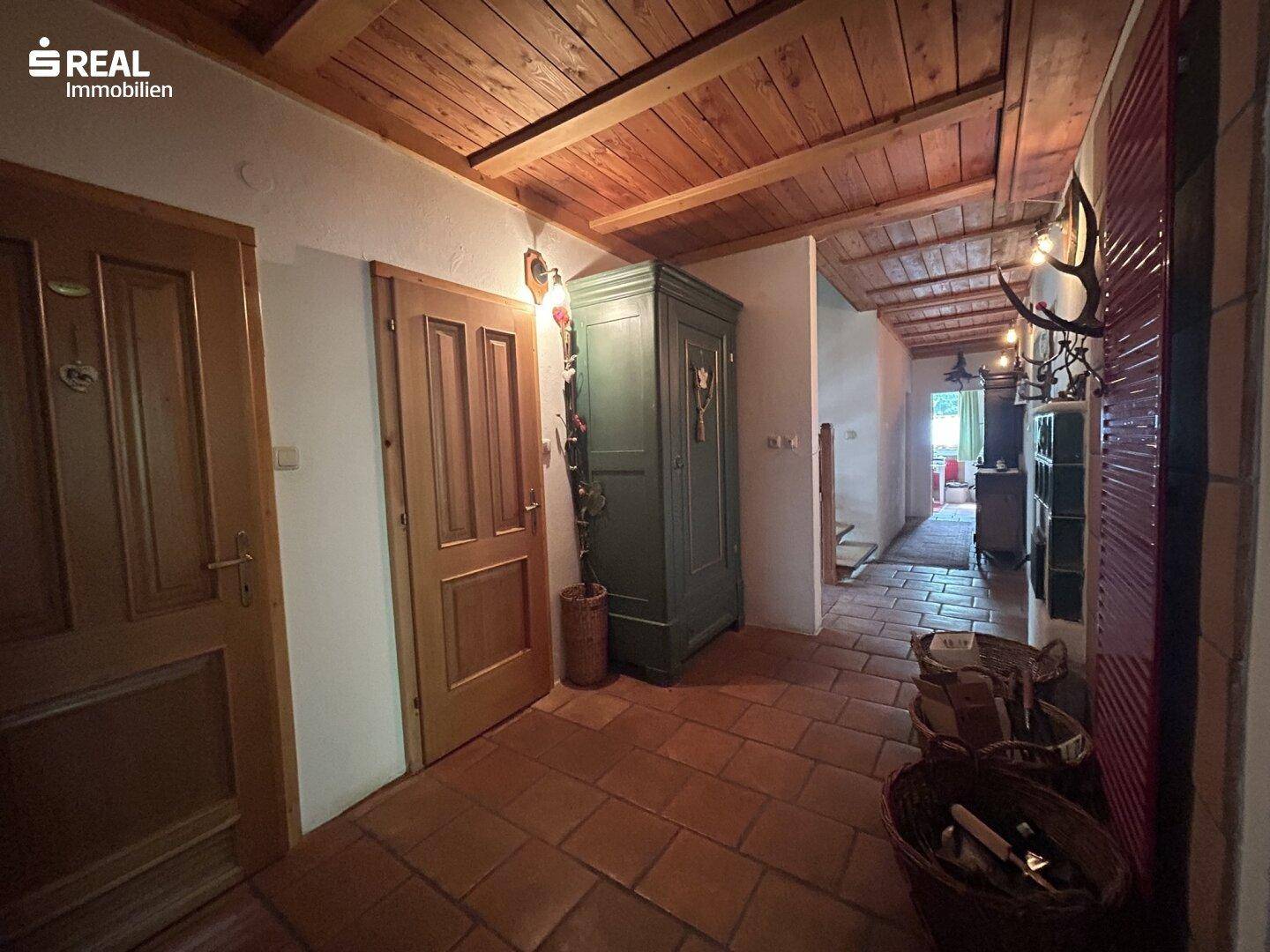 Traditioneller Flur mit Holzbalkendecke, Terrakottafliesen und rustikalen Möbeln.