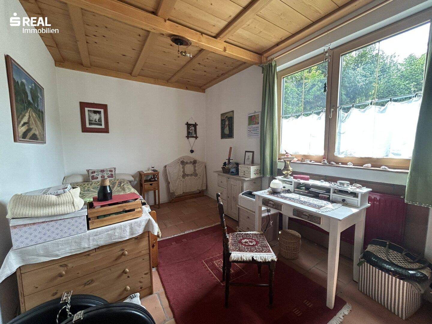 Helles Schlafzimmer mit Einzelbett, Schreibtisch und Terrakottafliesenboden.