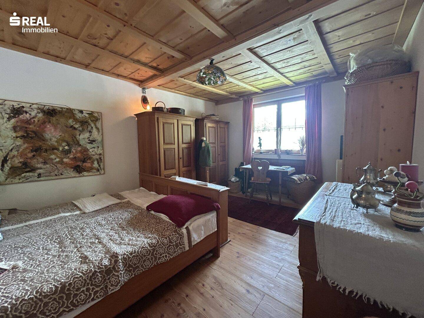 Geräumiges Schlafzimmer mit Doppelbett, Holzschränken und Holzbalkendecke.