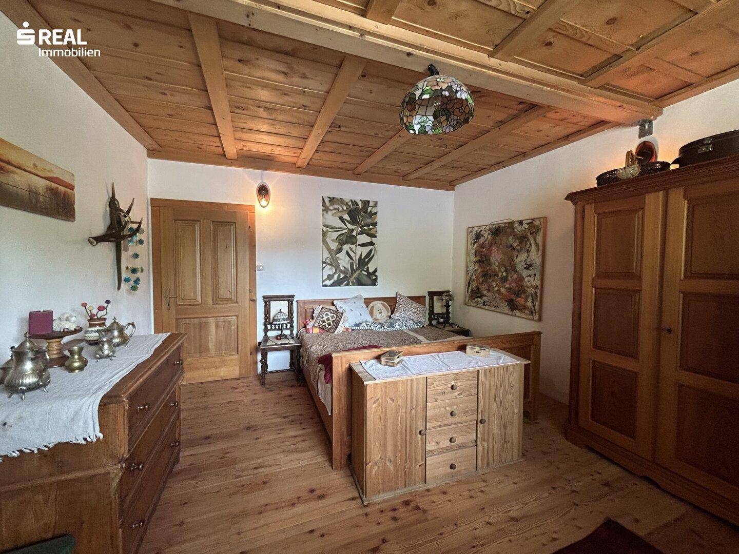 Gemütliches Schlafzimmer mit Holzbett, Holzbalkendecke und traditionellen Möbeln.