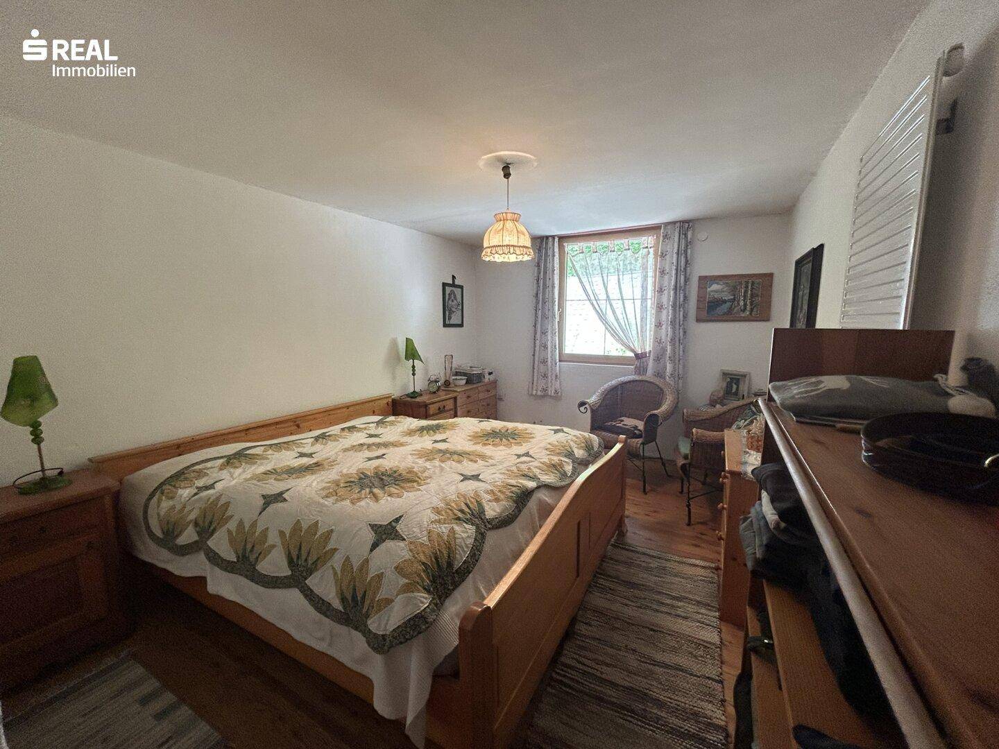 Komfortables Schlafzimmer mit Doppelbett, Teppich und schlichter Einrichtung.