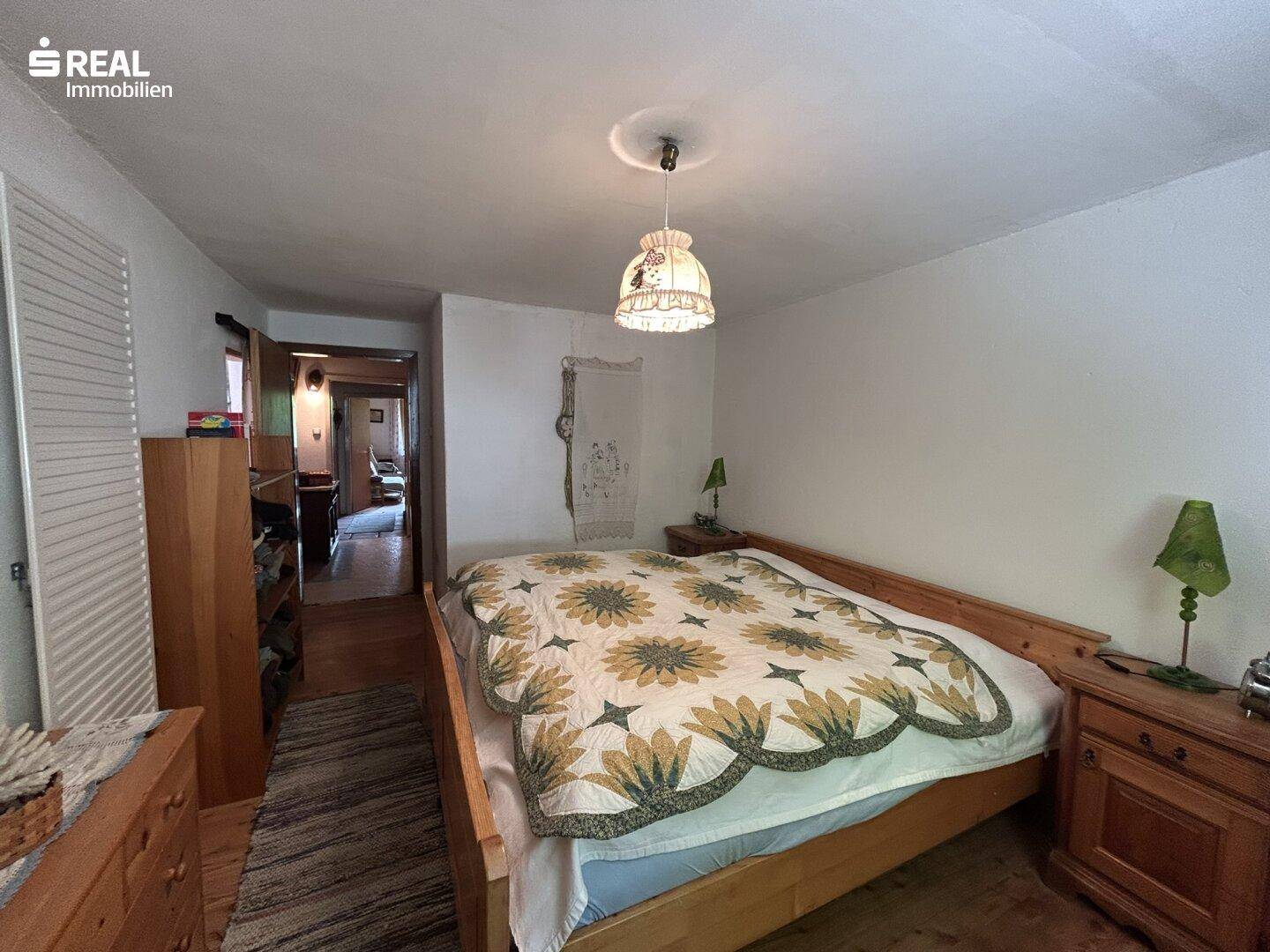 Helles Schlafzimmer mit Doppelbett und Zugang zu einem weiteren Raum.