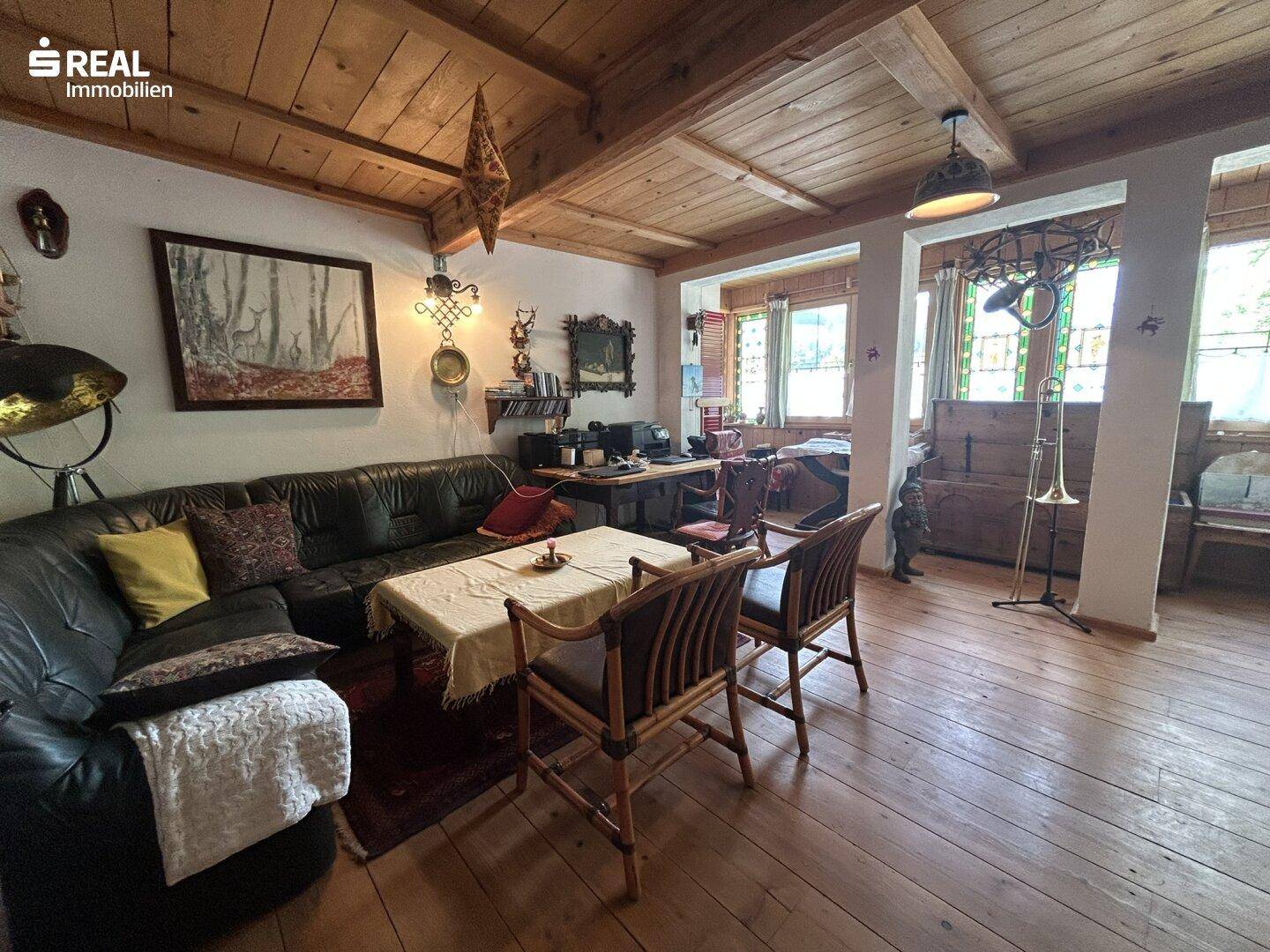 Helles Wohnzimmer mit Holzboden, traditioneller Einrichtung und Blick ins Grüne.