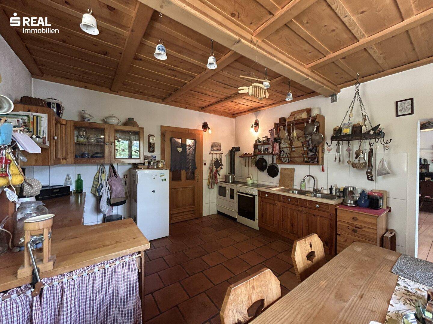 Rustikale Küche mit Holzschränken, traditionellem Herd und Terrakottafliesenboden.