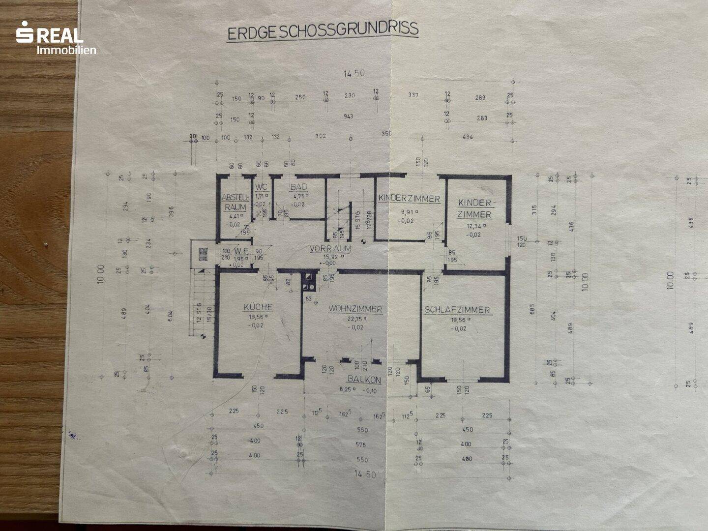 Grundriss des Erdgeschosses mit Küche, Wohnzimmer, Schlafzimmer, Kinderzimmern und Balkon.