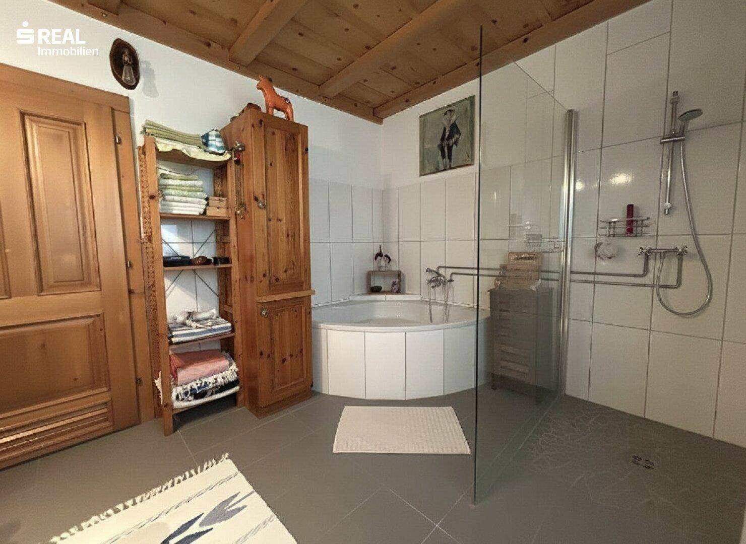 Geräumiges Badezimmer mit Eckbadewanne, Dusche und Holzbalkendecke.