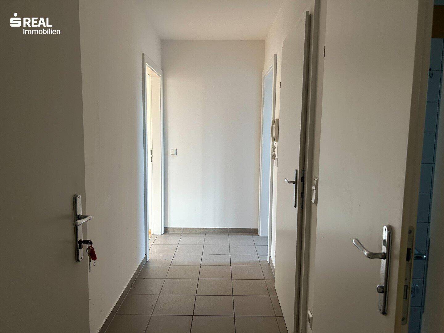 Heller Flur mit Fliesenboden und mehreren Türen zu angrenzenden Räumen.