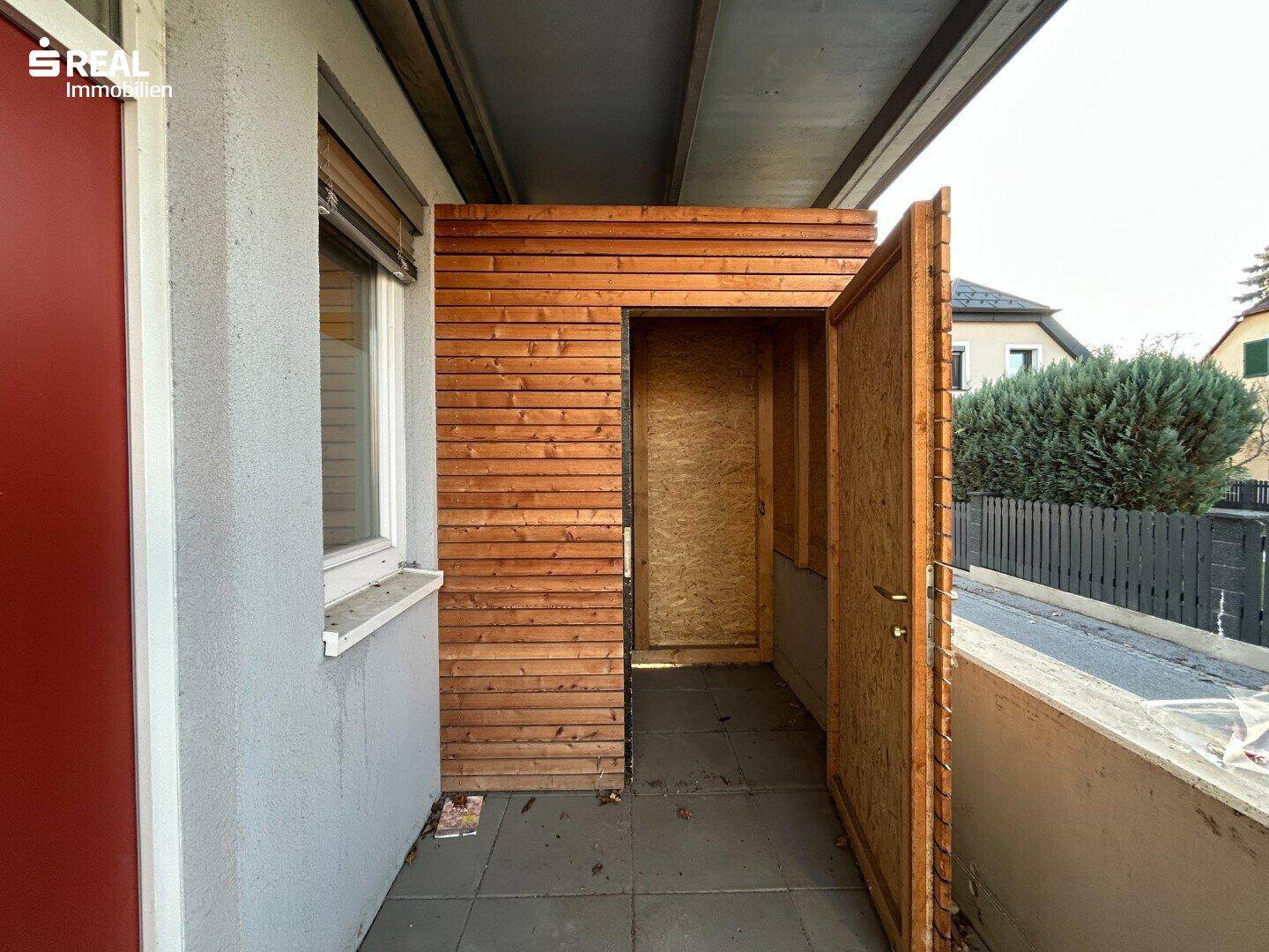 Balkon mit Holzverkleidung und einem kleinen, praktischen Abstellraum.