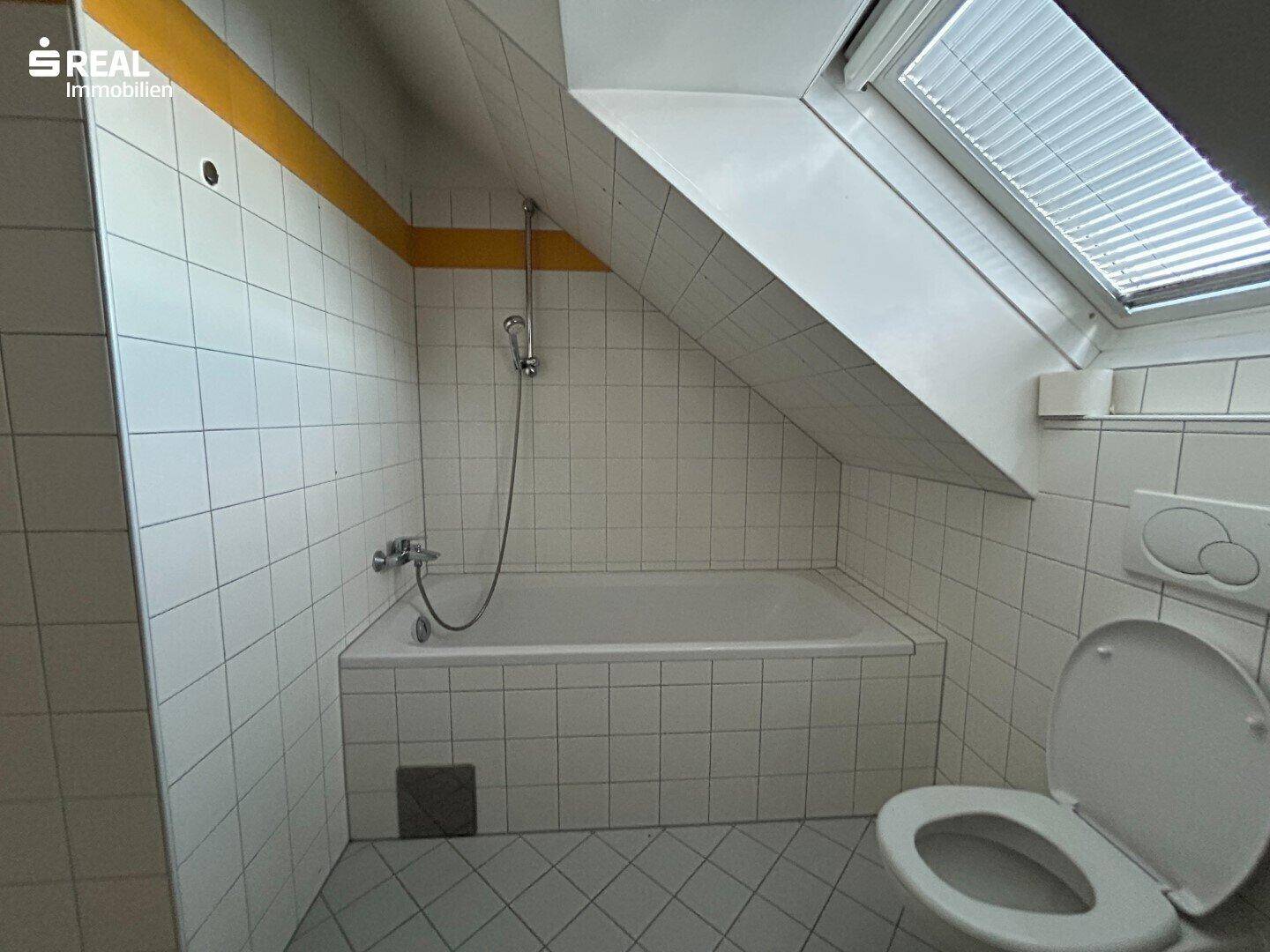 Badezimmer im Dachgeschoss mit Badewanne, WC und Dachfenster, hell und funktional.