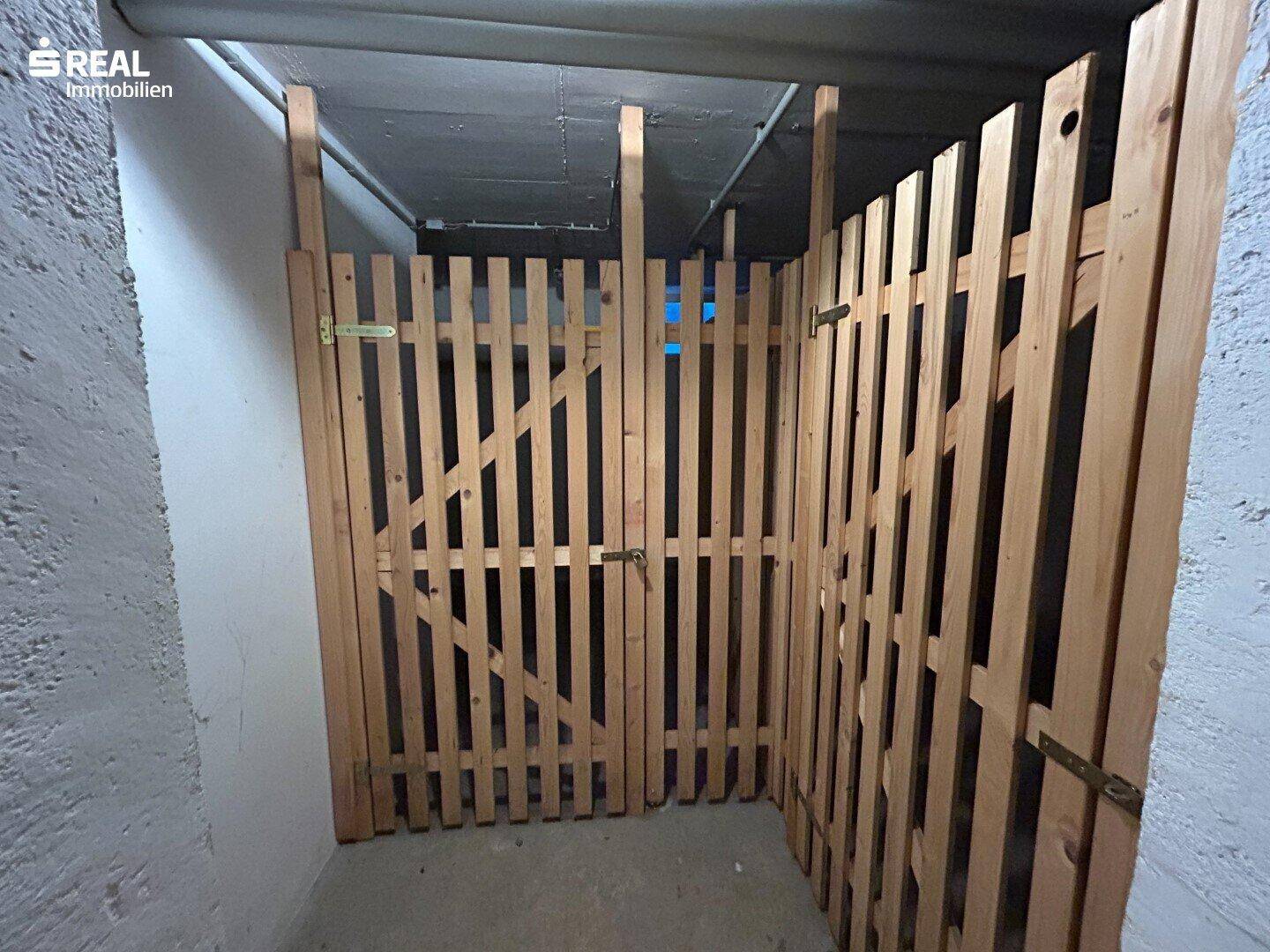 Abgetrennte Kellerabteile aus Holzlatten für zusätzlichen Stauraum im Untergeschoss.