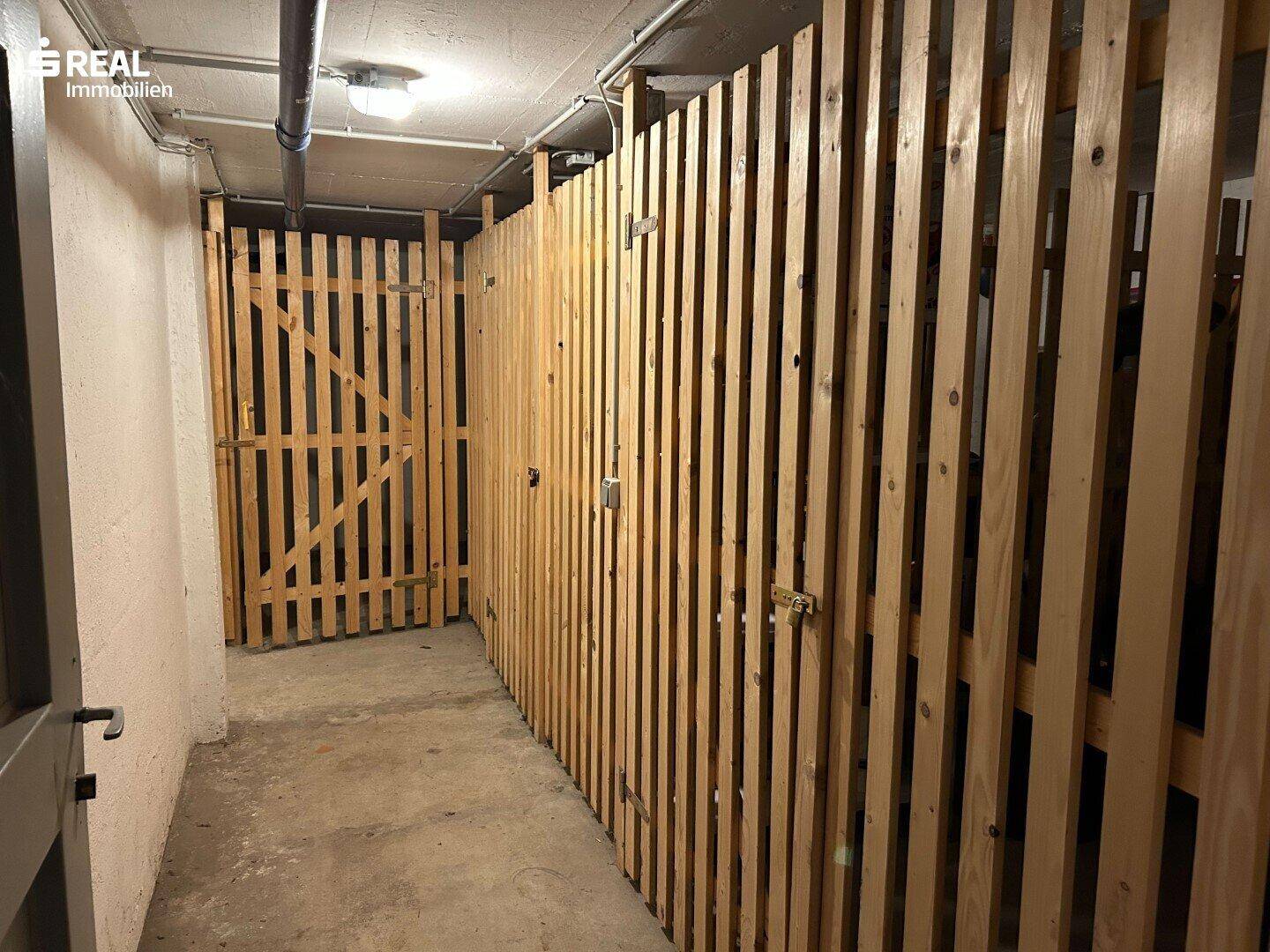 Kellerabteile mit Holzlattenwänden bieten zusätzlichen Stauraum im Untergeschoss.