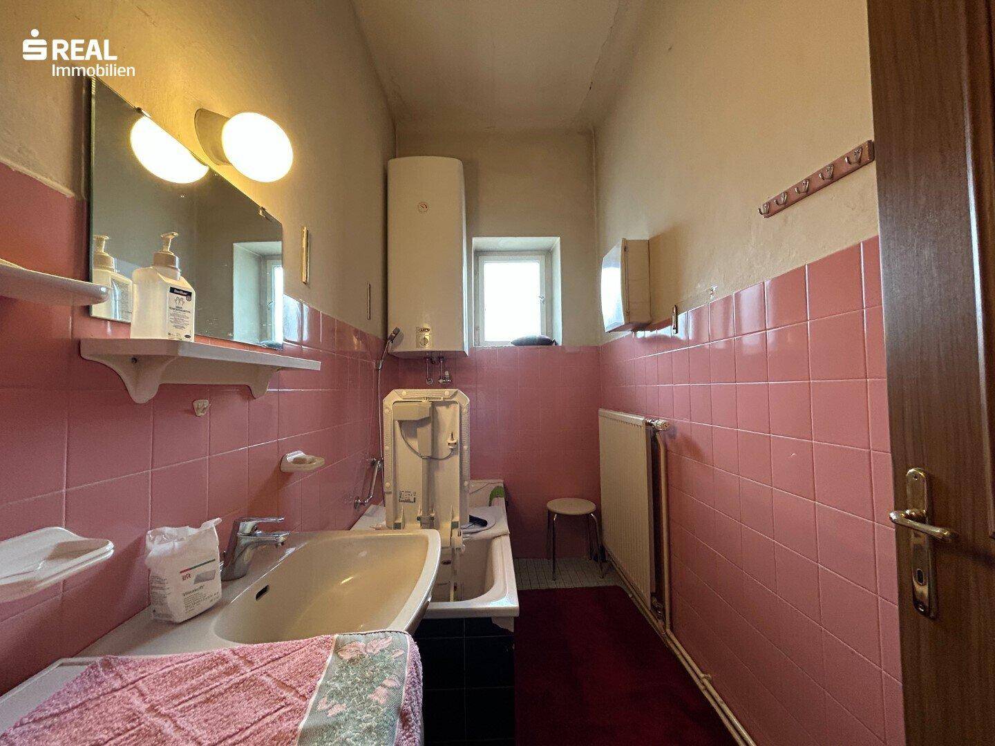 Badezimmer im 80er-Jahre-Stil mit rosa Fliesen, Waschbecken und Fenster.