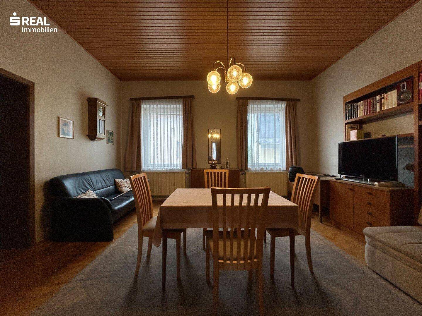 Klassisches Wohn-Esszimmer mit Holzboden, Esstisch und bequemen Sitzgelegenheiten.