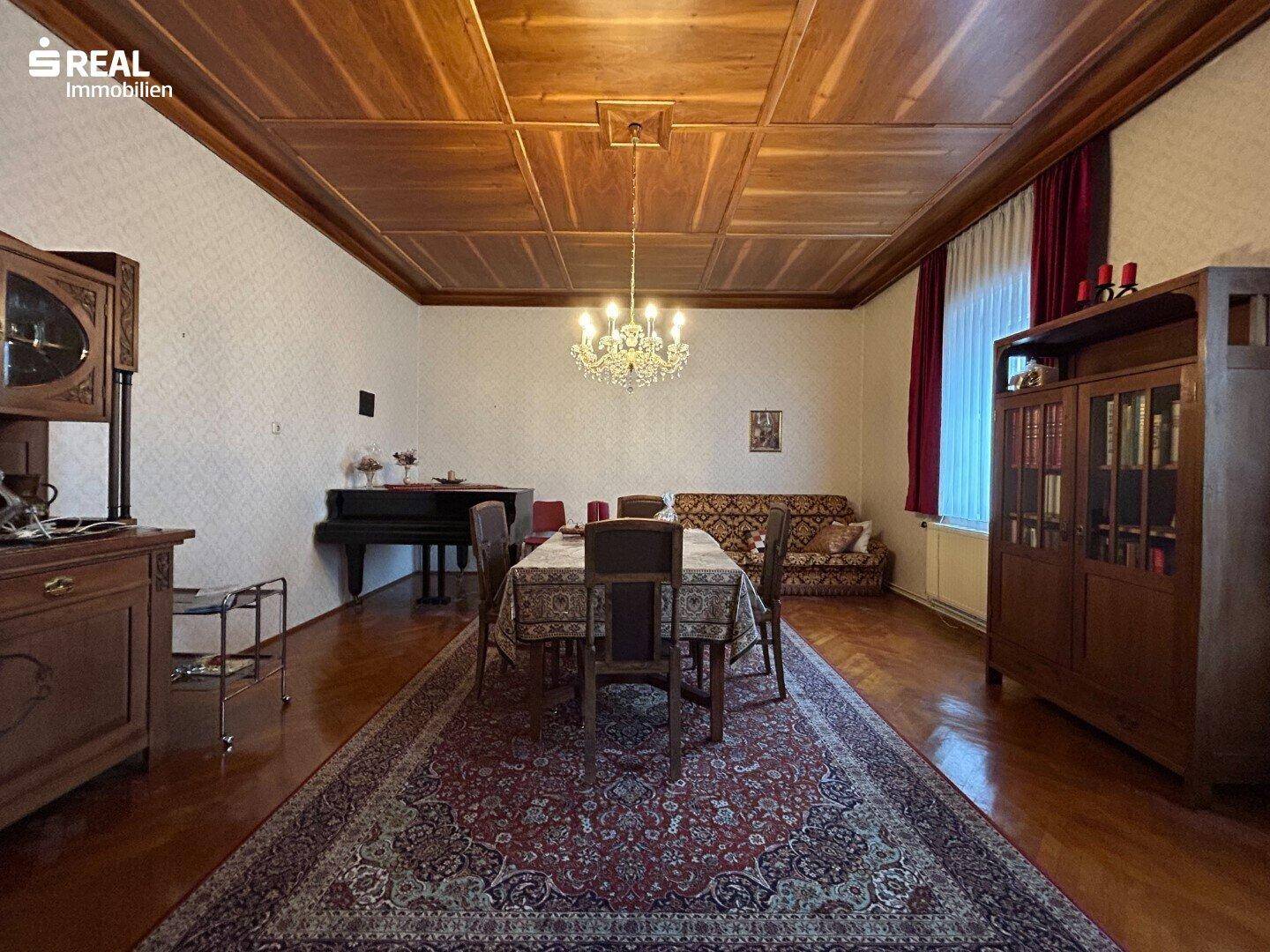 Elegantes Esszimmer mit Holzboden, Kronleuchter und einem großen Esstisch mit Teppich.