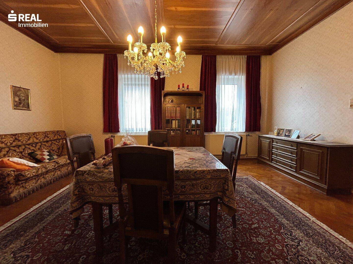 Klassisches Esszimmer mit Holzboden, Kronleuchter und antiken Möbeln, ideal für Gäste.