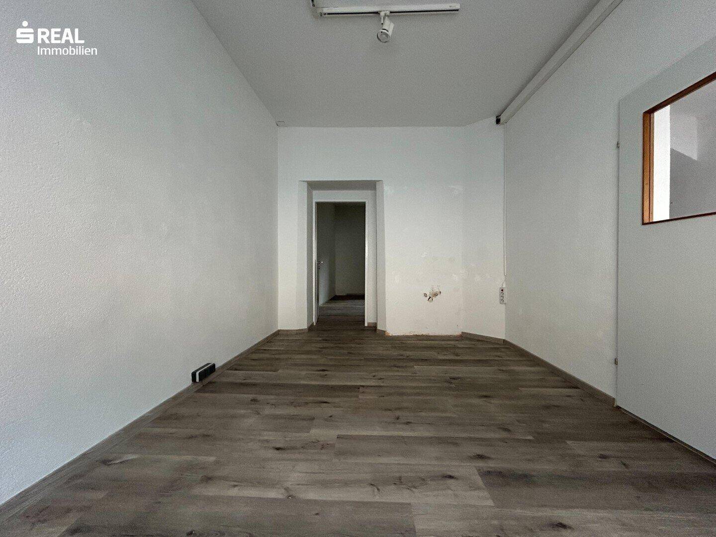Heller, leerer Raum mit Holzboden und weiß gestrichenen Wänden, bereit zur Nutzung.