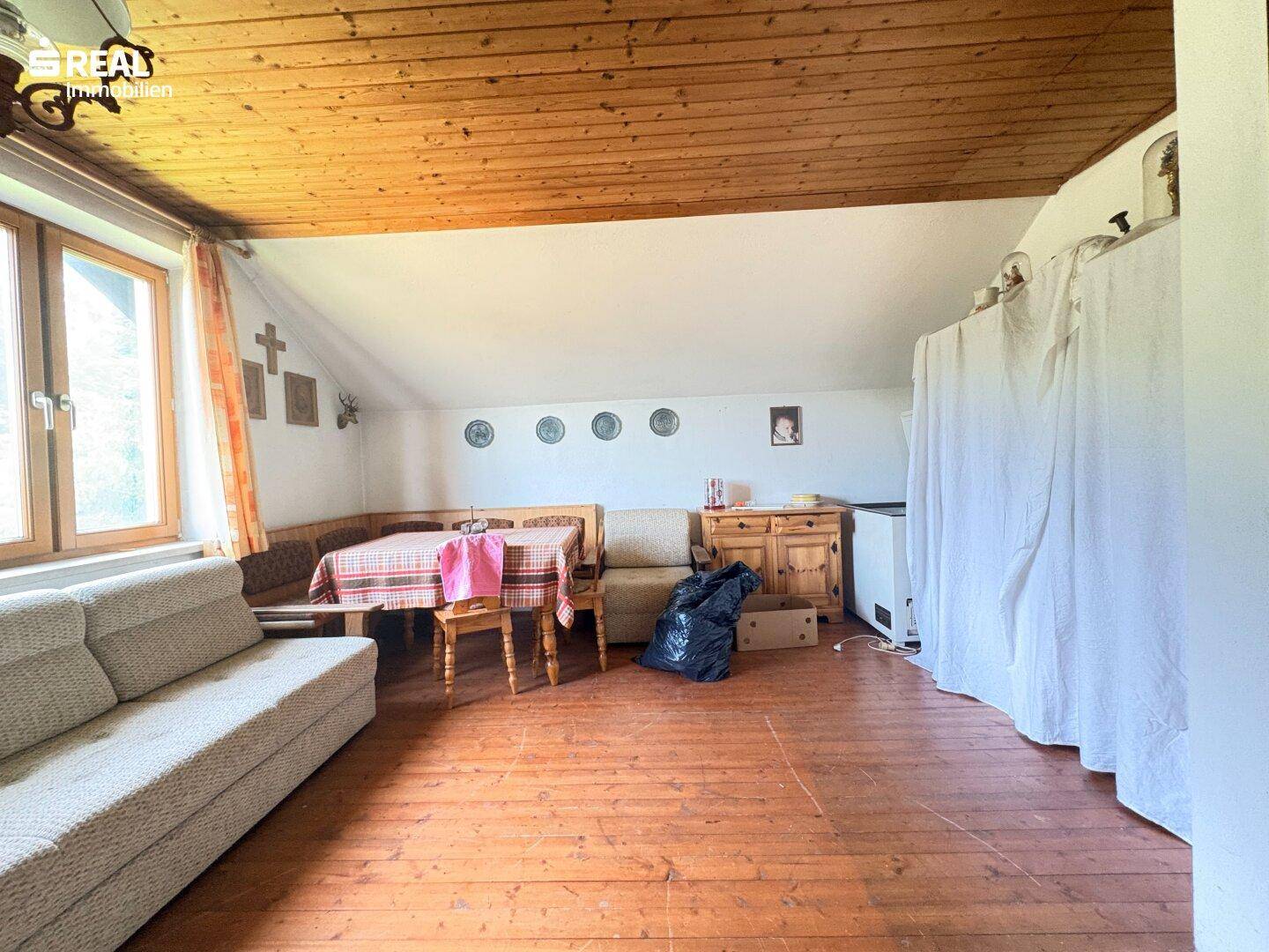 Gemütlicher Wohn-Essbereich mit Holzbalkendecke, Dielenboden und traditioneller Eckbank.