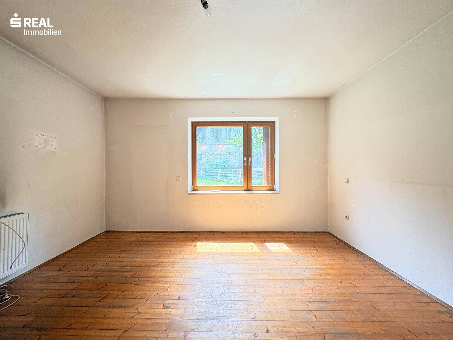 Leeres Zimmer mit Holzdielenboden und einem Fenster, bereit zur individuellen Gestaltung.