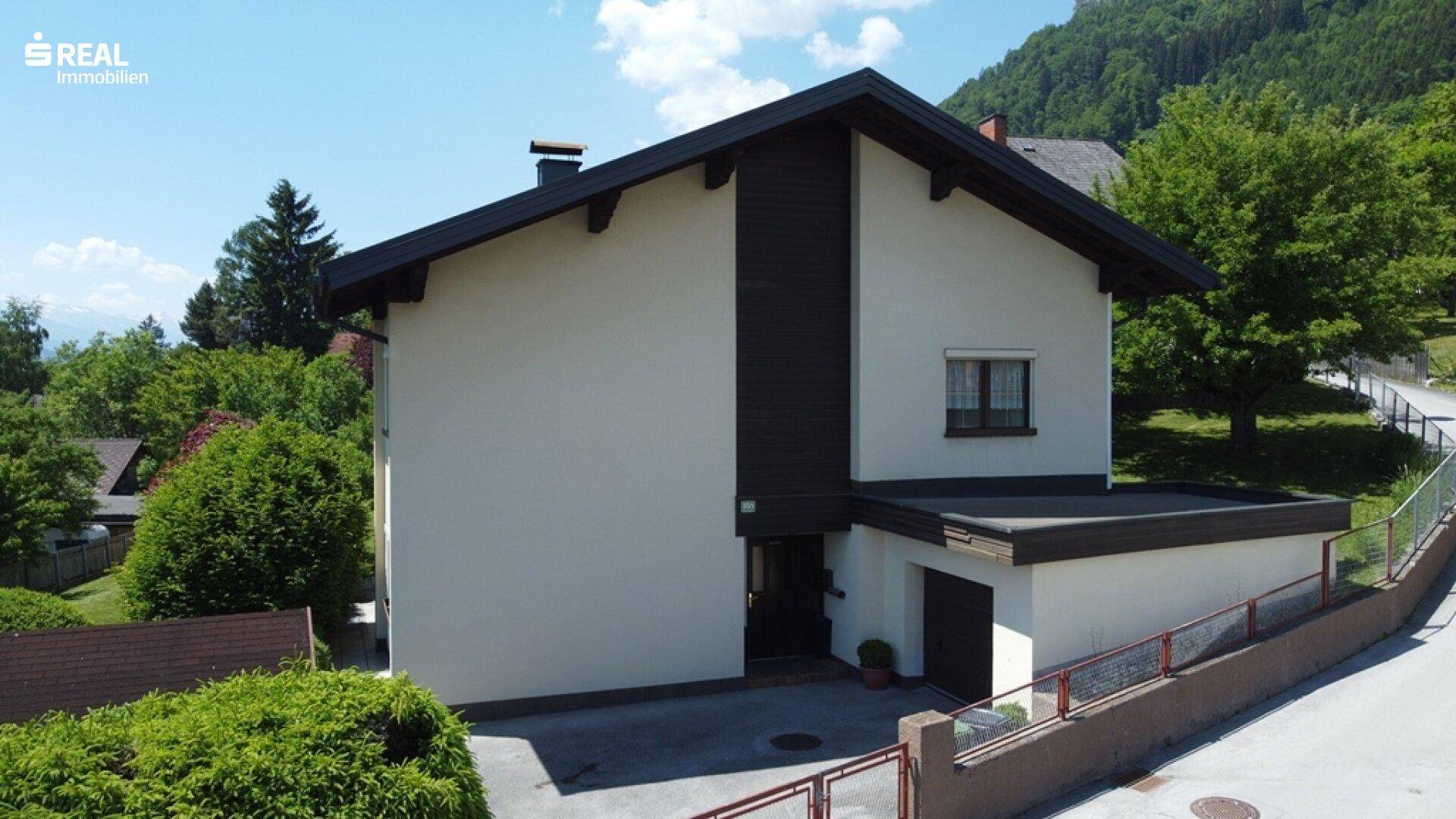 Vorderansicht des Hauses mit integrierter Garage und gepflegter Zufahrt unter blauem Himmel.