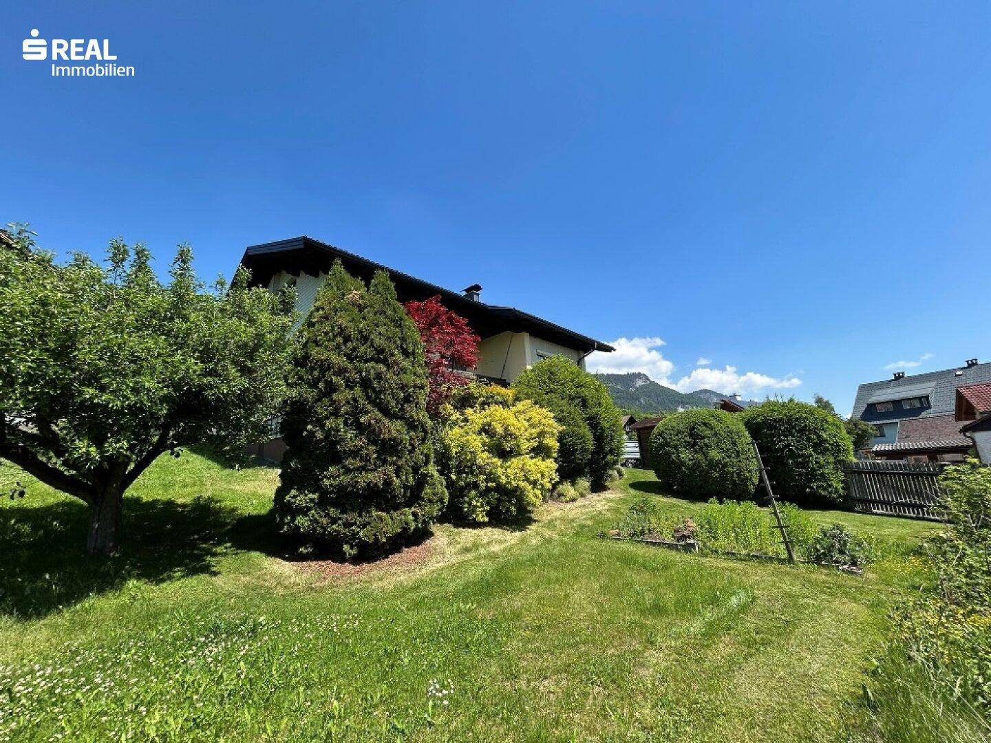 Weitläufiger Garten mit altem Baumbestand und Blick auf die umliegende Berglandschaft.