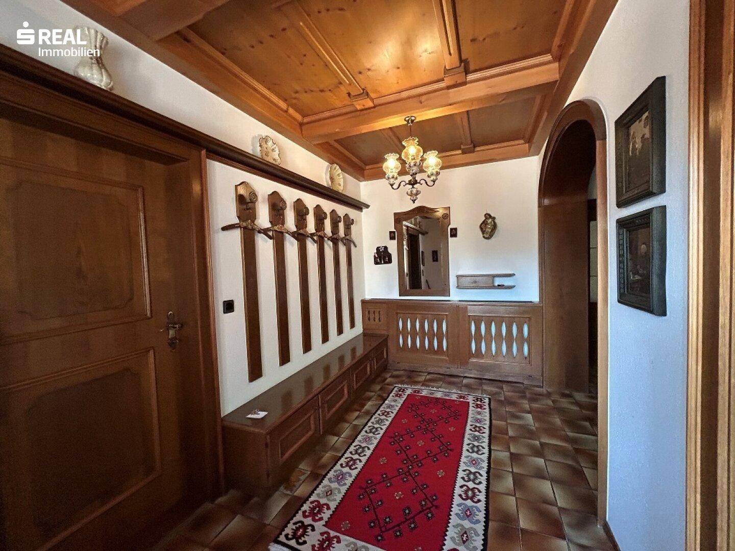 Gemütlicher Eingangsbereich mit Holzvertäfelung, Garderobe und traditionellem Teppich.