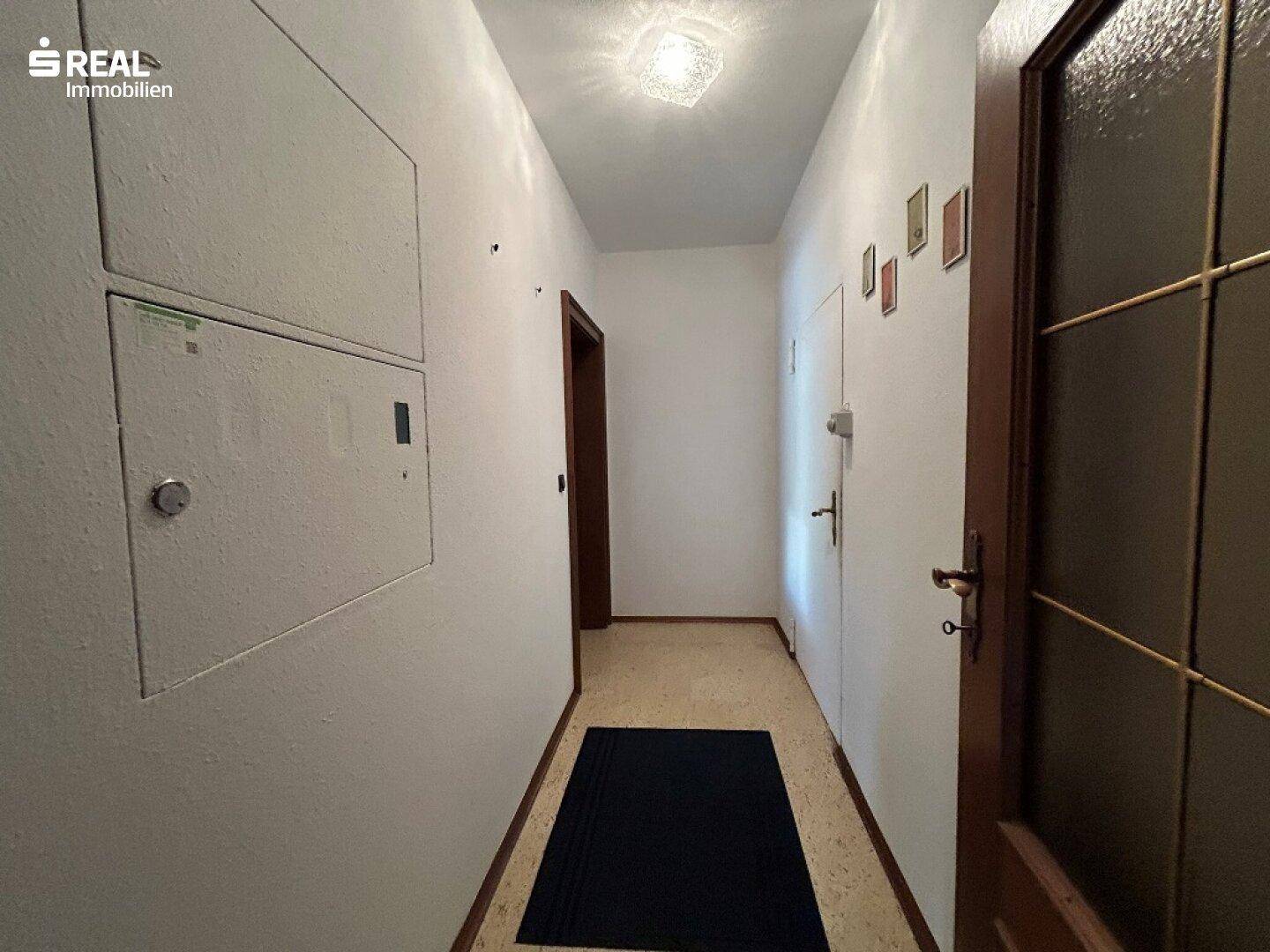 Heller Flur mit schlichtem Design und funktionalem Bodenbelag, verbindet die Räume.