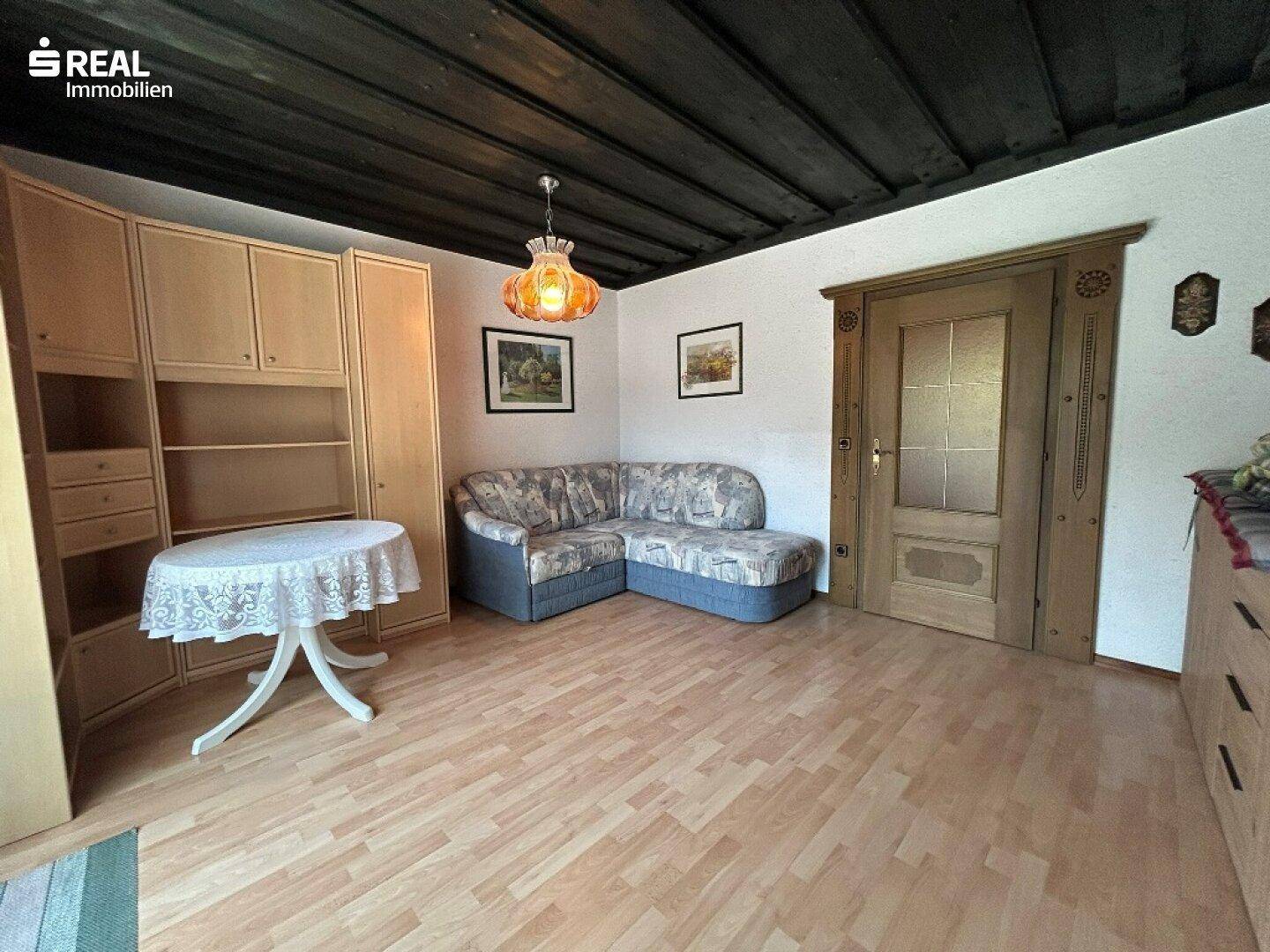 Wohnzimmer mit Ecksofa, Holzdecke und traditionellen Möbeln, schafft eine warme Atmosphäre.