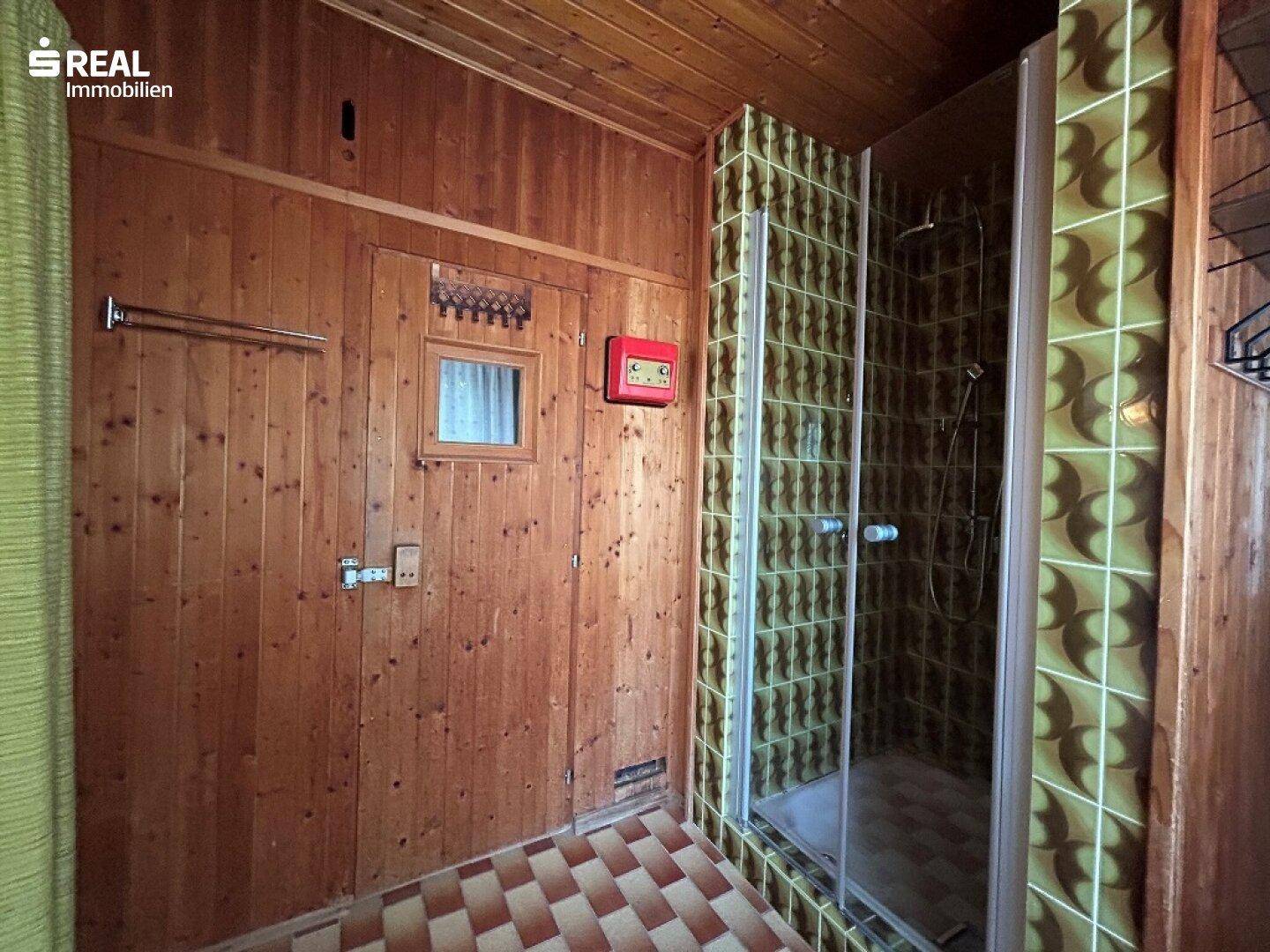 Rustikales Badezimmer mit Holzvertäfelung und gefliester Duschkabine, im traditionellen Stil.