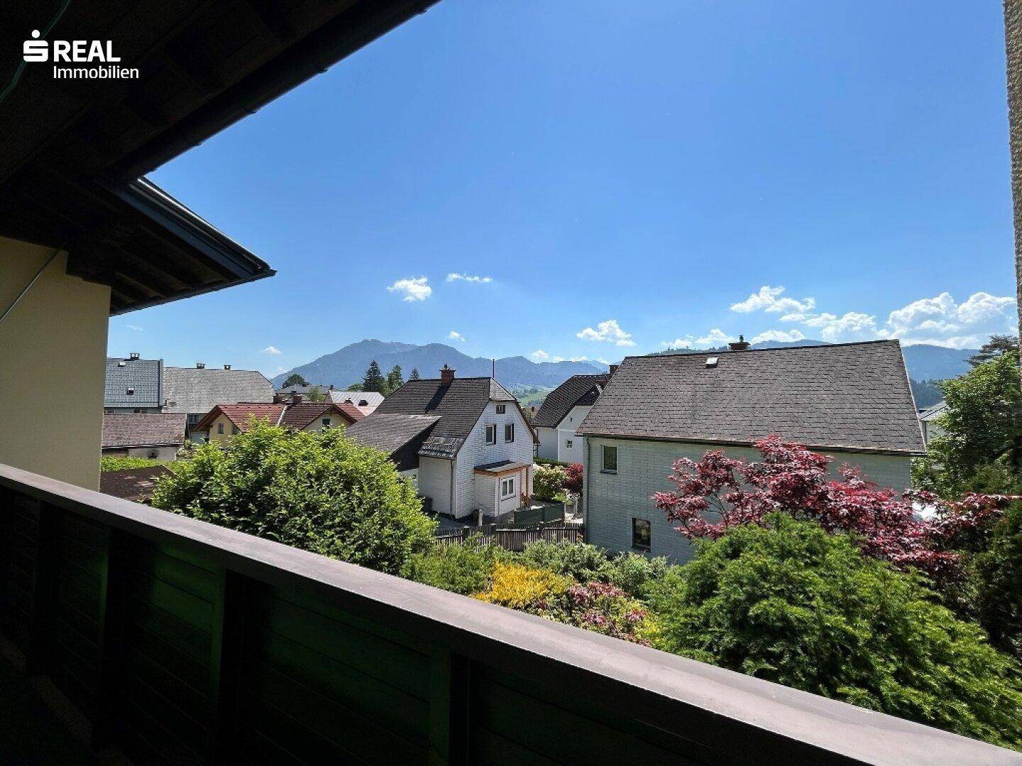 Panoramablick vom Balkon auf die umliegende Berglandschaft und die charmante Dorfbebauung.