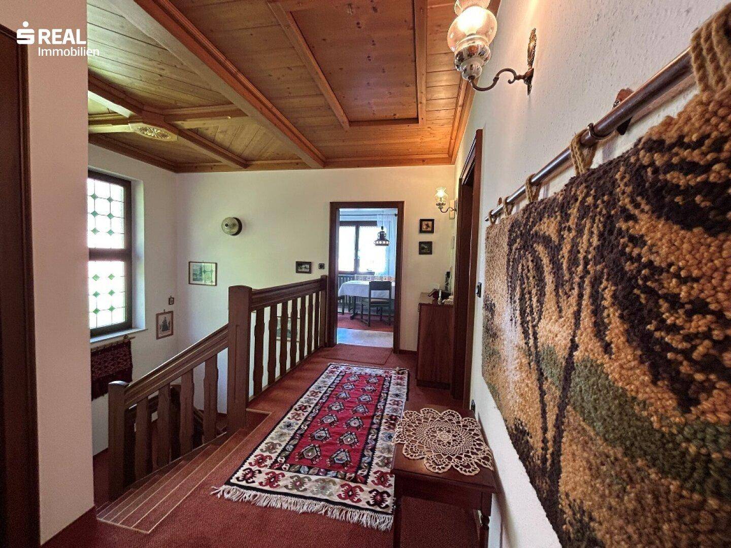 Heller Flur mit traditionellem Teppich, Bleiglasfenster und Blick in einen angrenzenden Wohnbereich.