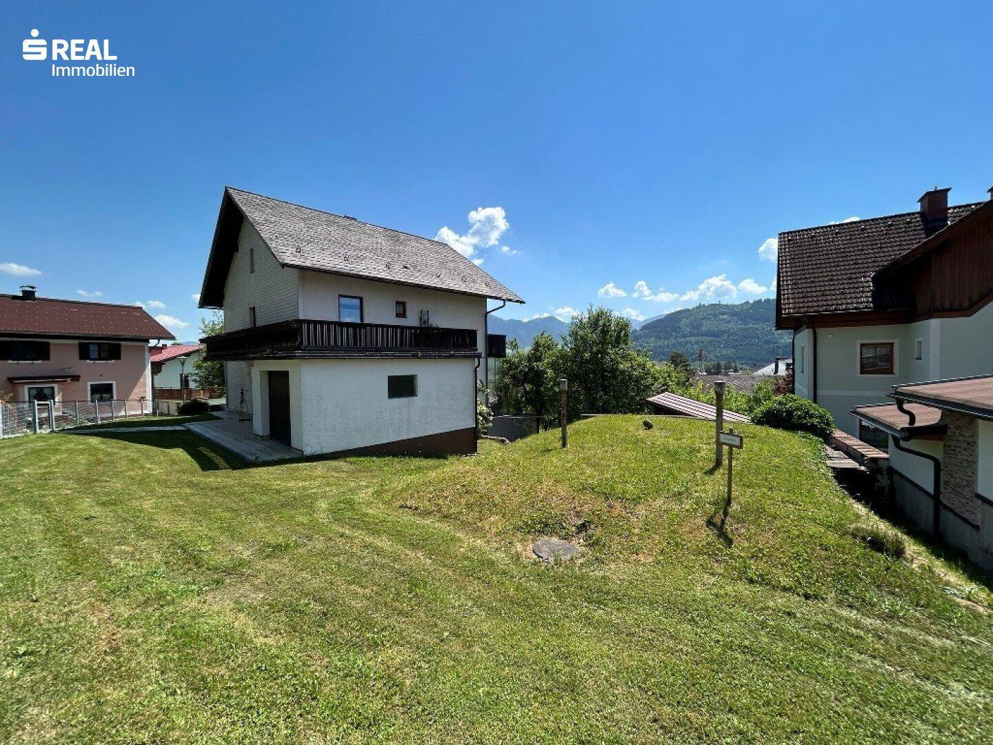 Weitläufiger Gartenbereich mit Blick auf das Haus und die malerische Bergkulisse im Hintergrund.