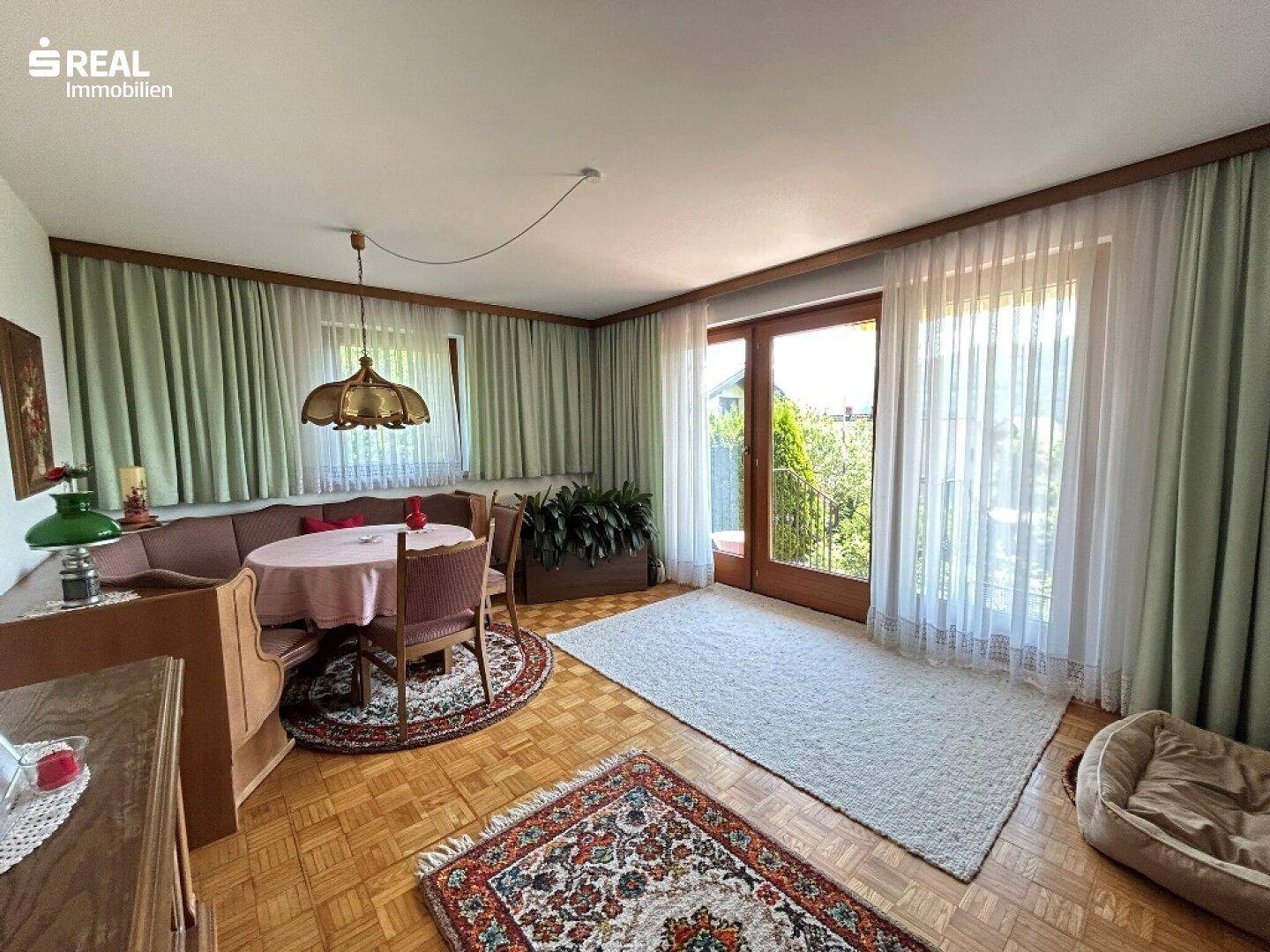 Gemütlicher Wohn- und Essbereich mit Parkettboden und Zugang zur Terrasse, hell und einladend.