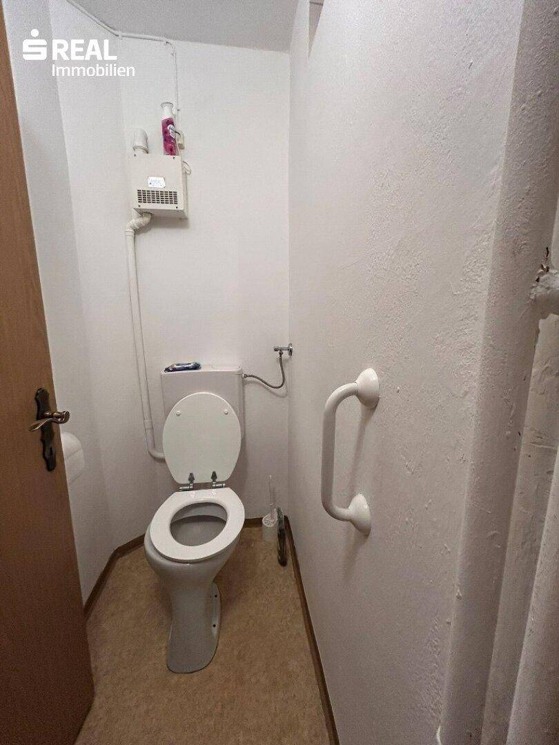 Separates WC mit Toilette und Haltegriff, funktional und barrierefrei ausgestattet.