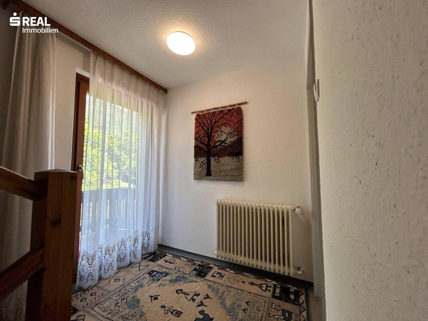 Heller Flurbereich mit Zugang zum Balkon und einem Fenster, das viel Licht spendet.