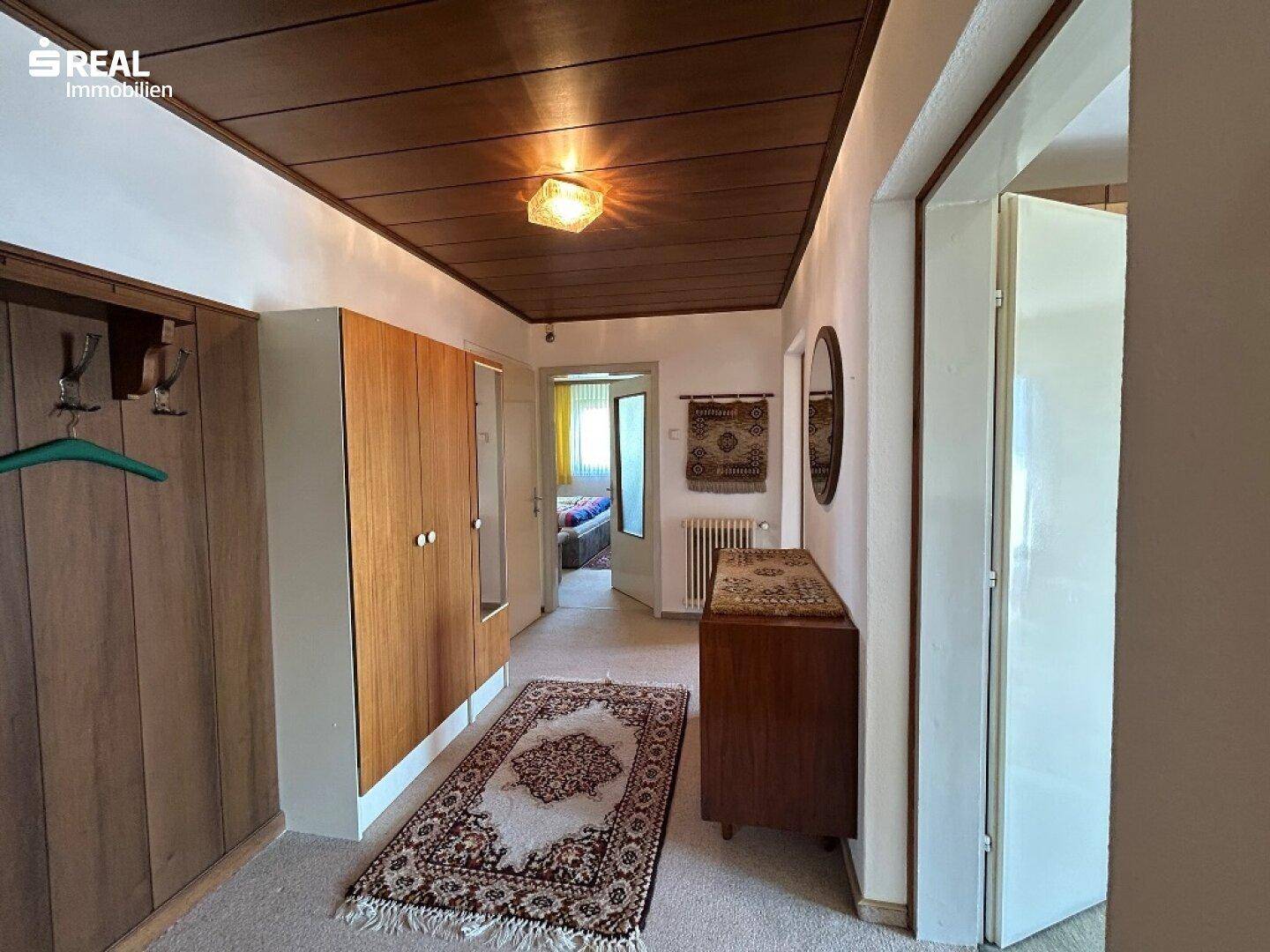 Geräumiger Flur mit Holzdecke, Teppichboden und Einbauschränken, die viel Stauraum bieten.