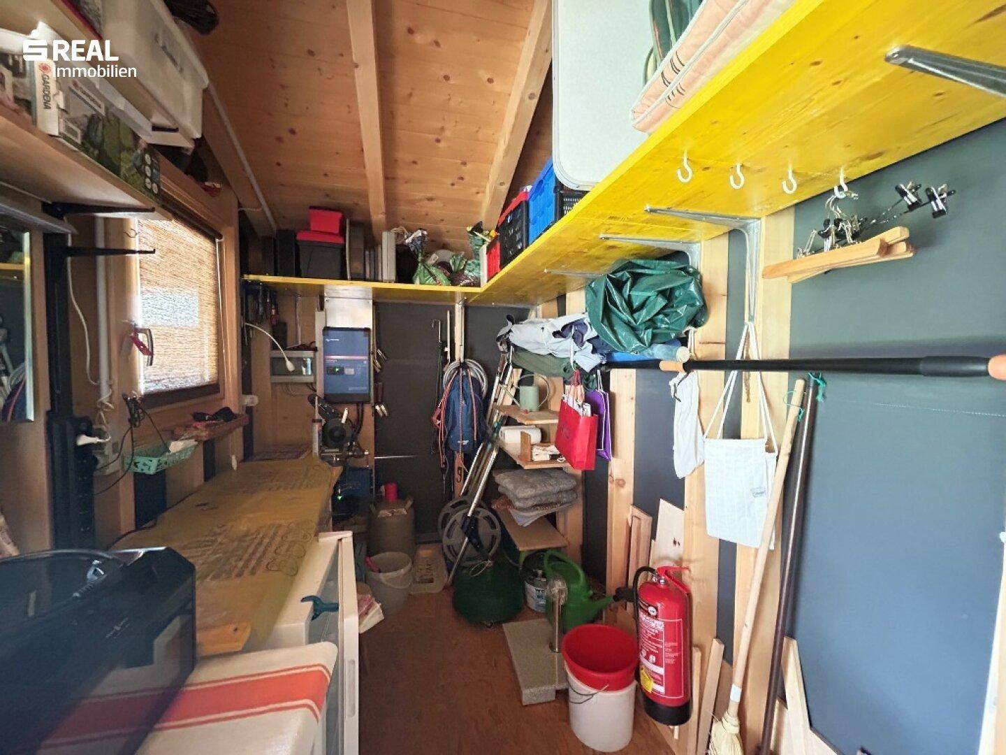 Praktischer Abstellraum mit Holzverkleidung, Regalen und viel Stauraum für diverse Gegenstände.