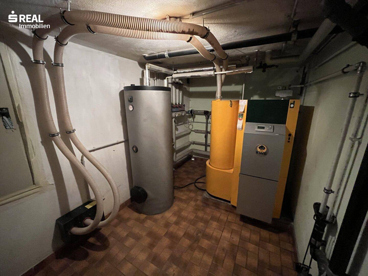 Heizungsraum mit moderner Heizungsanlage und Warmwasserspeicher im Keller.