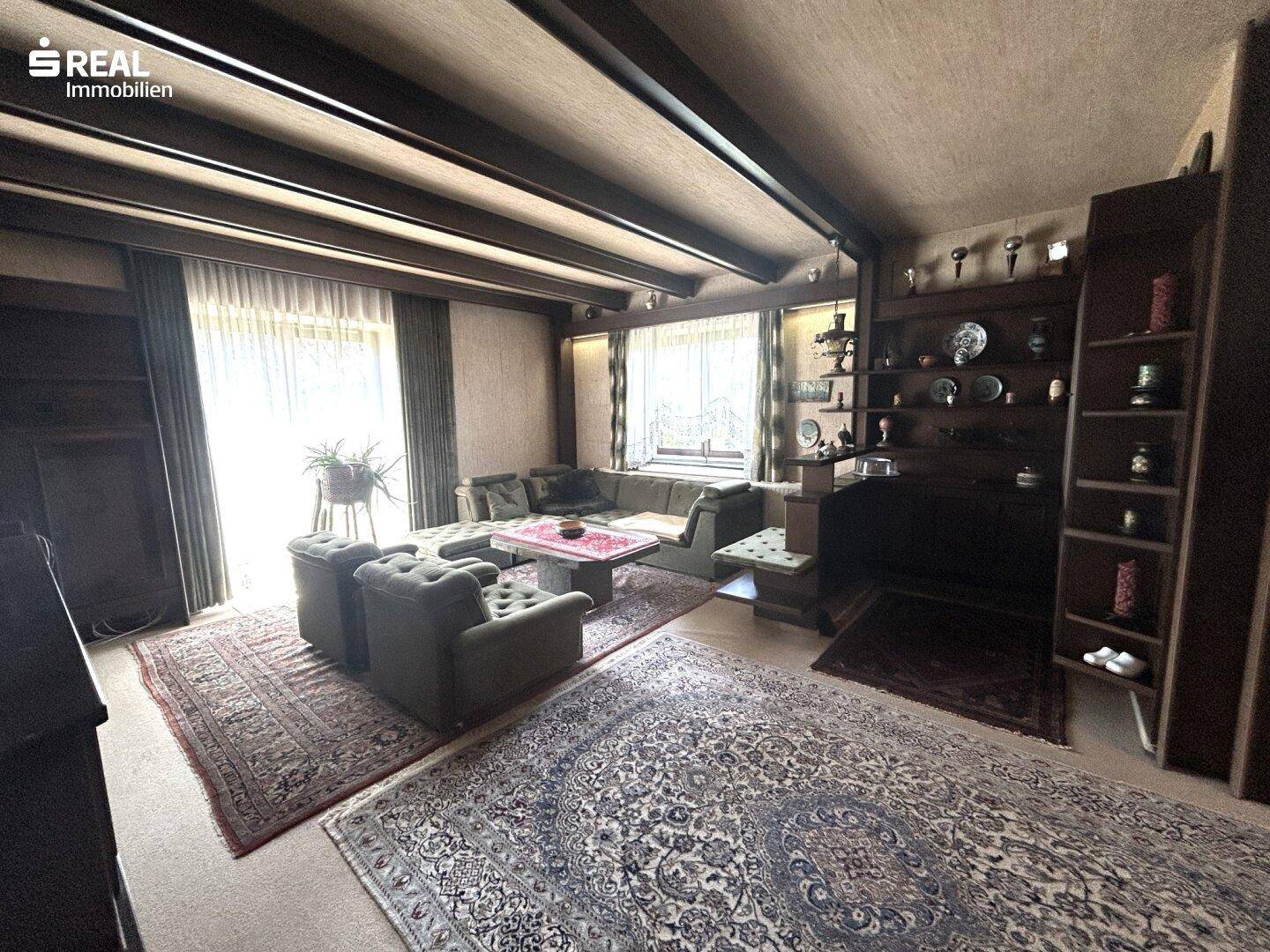 Geräumiges Wohnzimmer mit Holzbalkendecke, Teppichen und traditioneller Einrichtung.