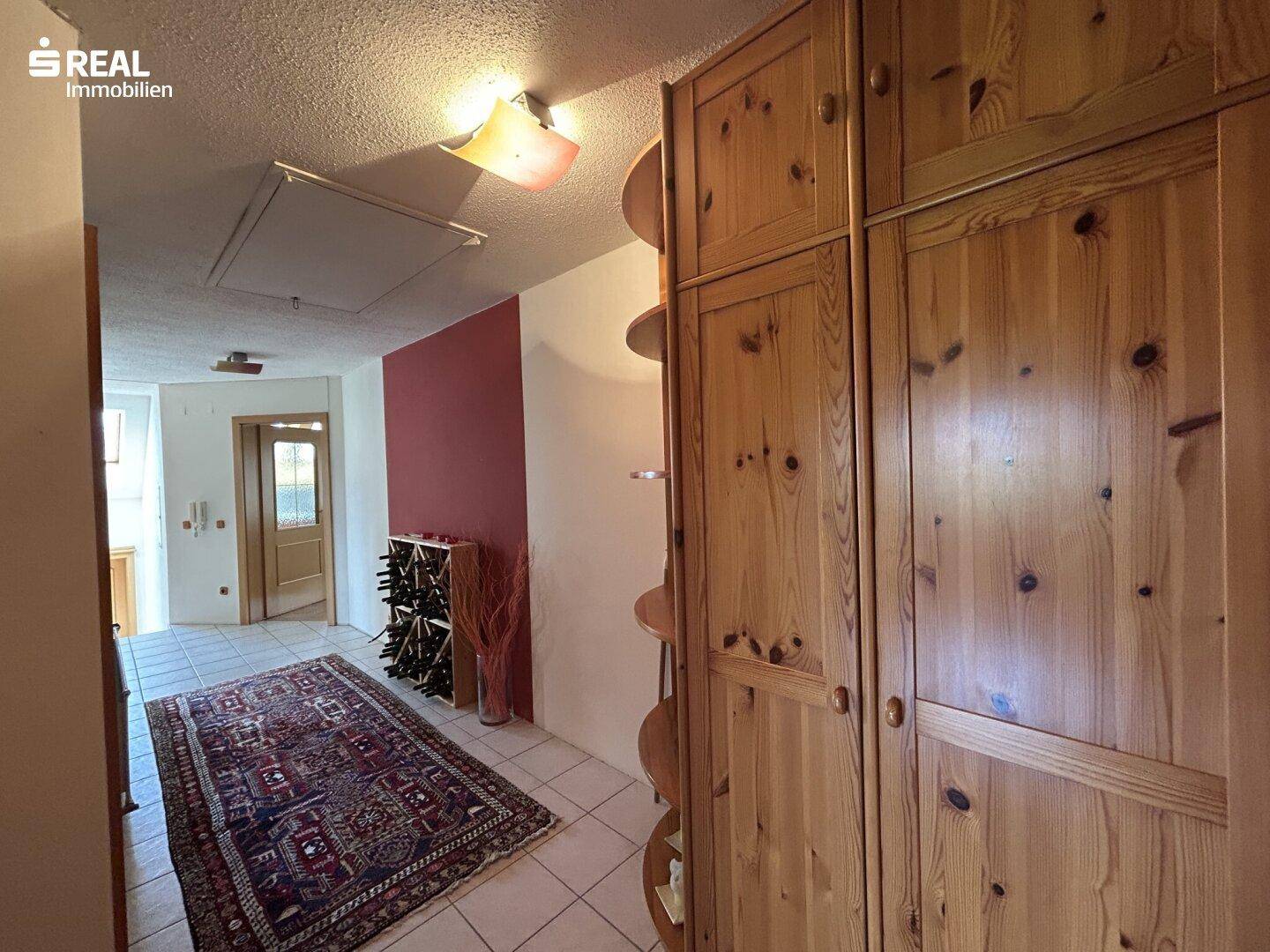 Eingangsbereich mit Fliesenboden, einem Weinregal und rustikalen Einbauschränken aus Holz.