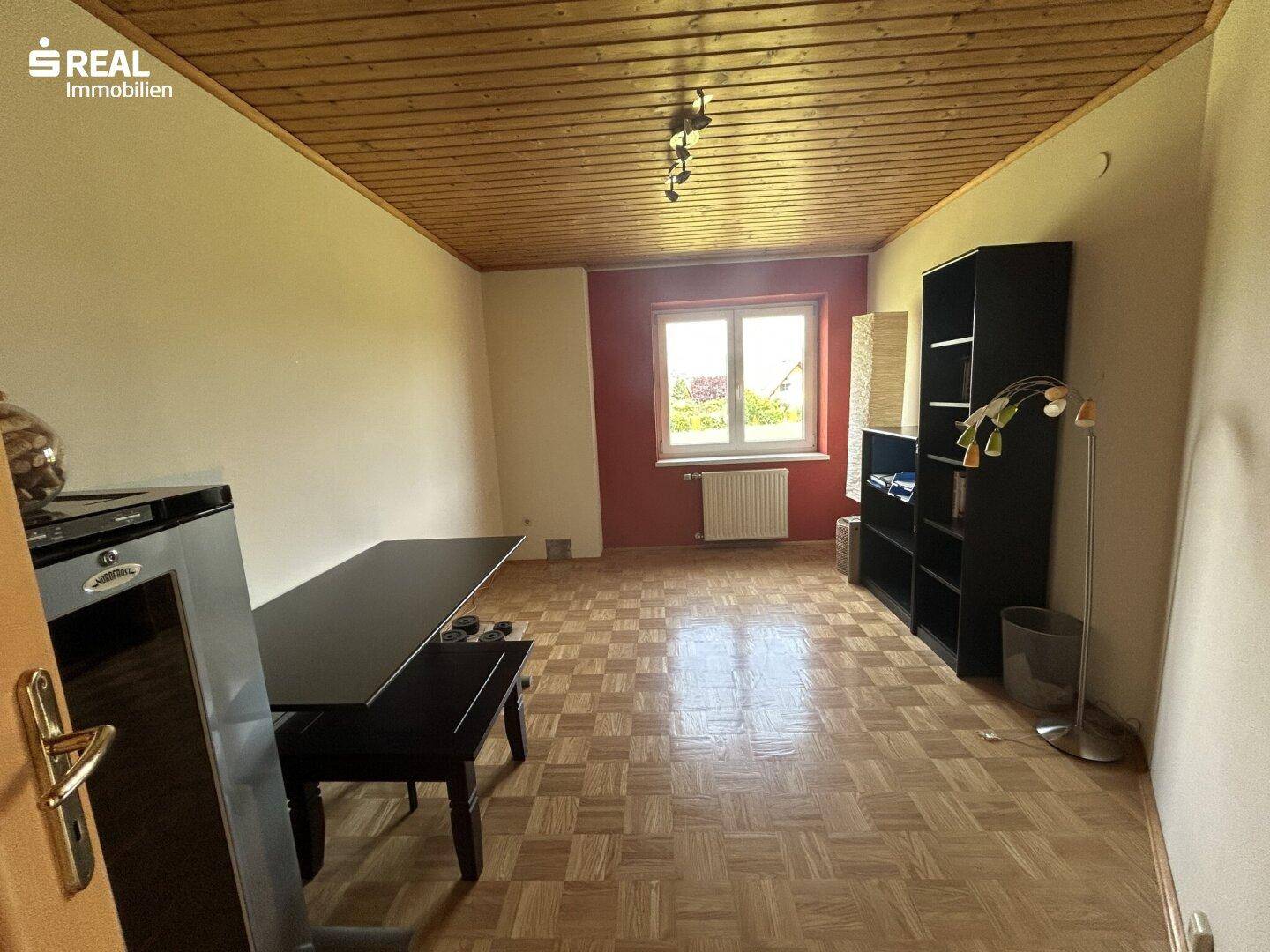 Heller Raum mit Parkettboden, Holzdecke und einem Fenster, ideal als Esszimmer oder Büro.