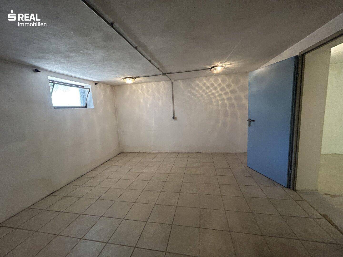 Leerer Kellerraum mit Fliesenboden und einem kleinen Fenster, bietet zusätzlichen Stauraum.