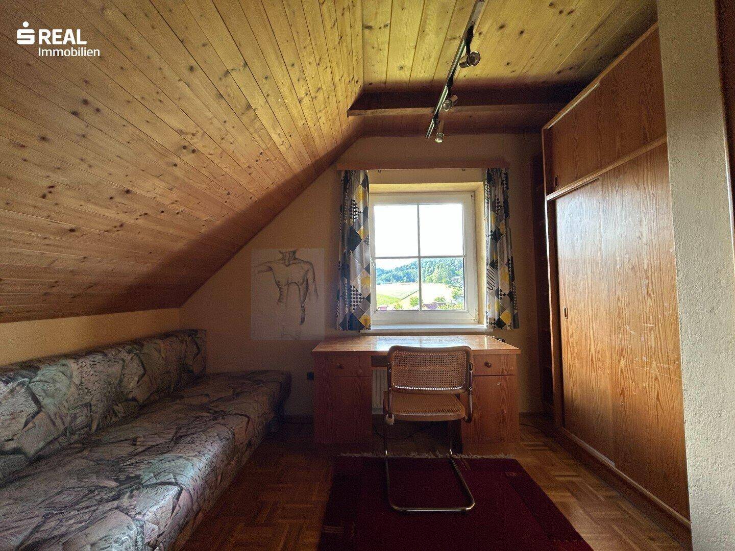 Gemütliches Dachzimmer mit schräger Holzdecke, Parkettboden, einem Schlafsofa und Fenster mit Ausblick.