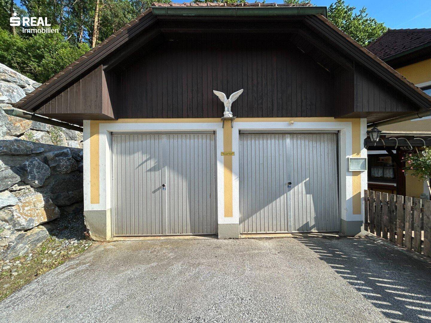 Doppelgarage mit zwei Holztoren, harmonisch in die Architektur des Hauses integriert.