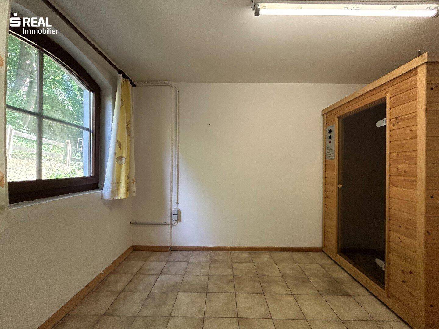 Raum mit einer Saunakabine, Fliesenboden und einem Fenster, ideal für Wellness.